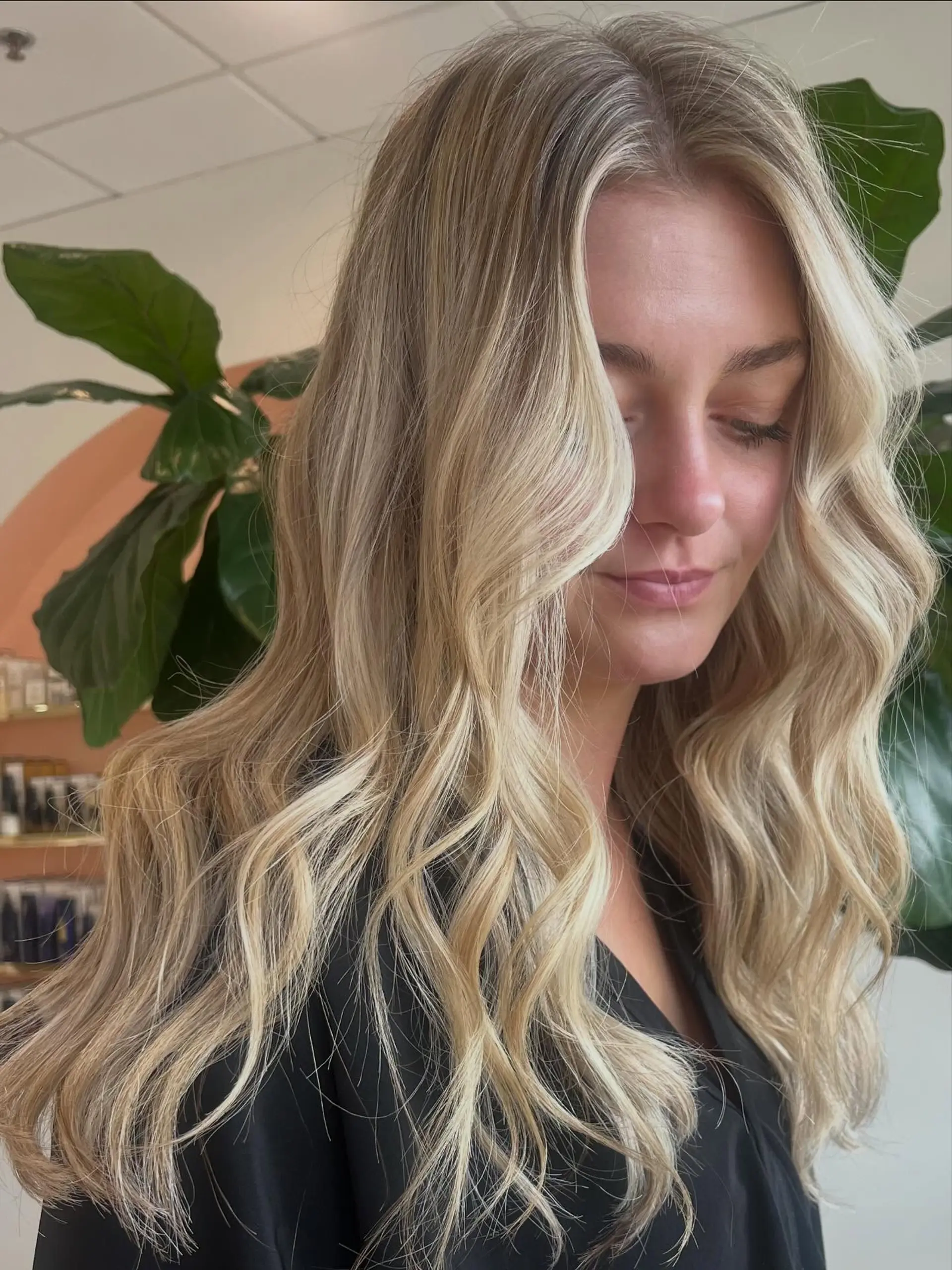 Long hair featuring a dimensional blonde balayage with bright face-framing pieces and styled in loose beach waves. 1