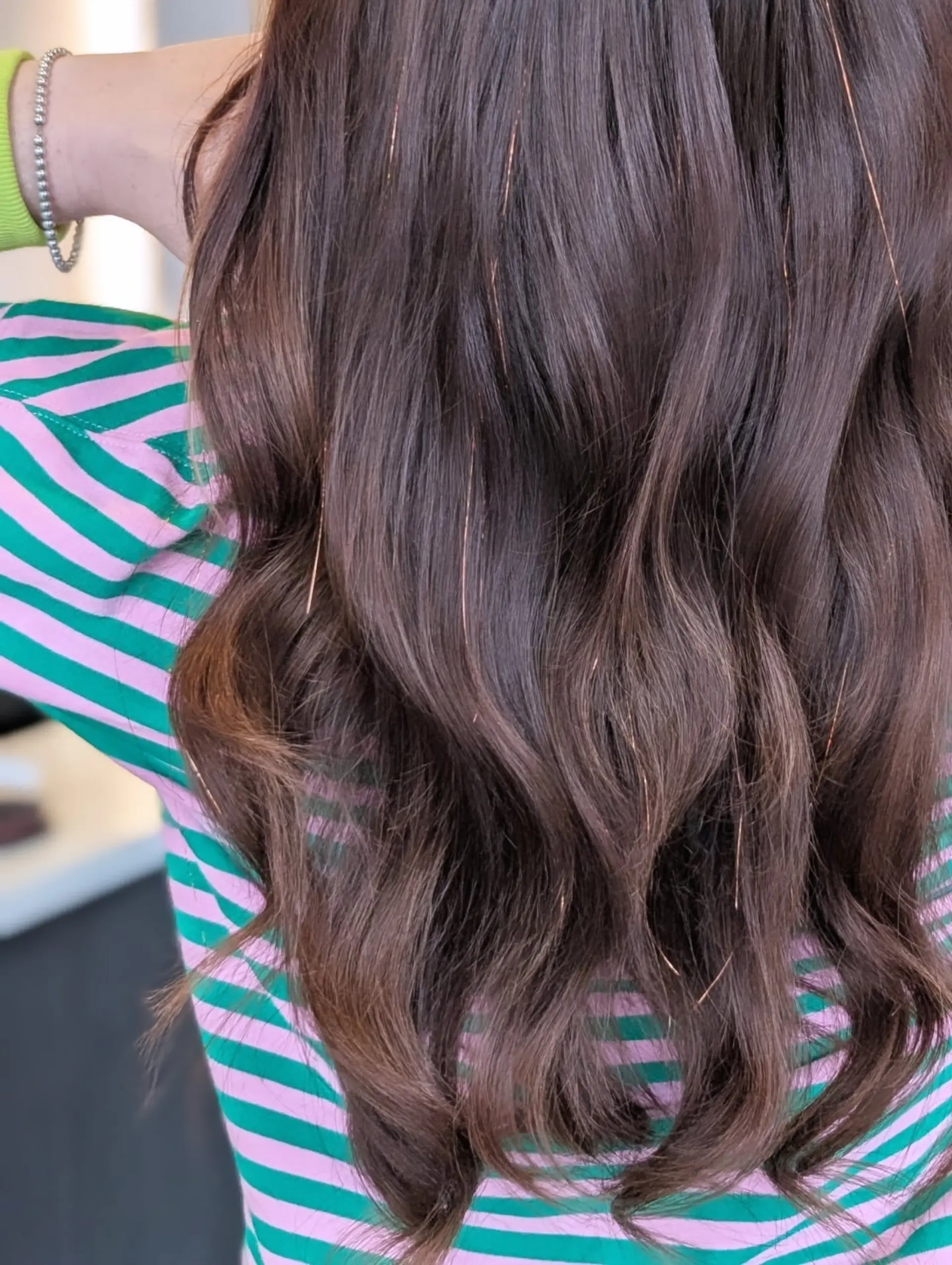 Long brunette hair styled in soft, loose waves accented with shimmering copper hair tinsel. 1