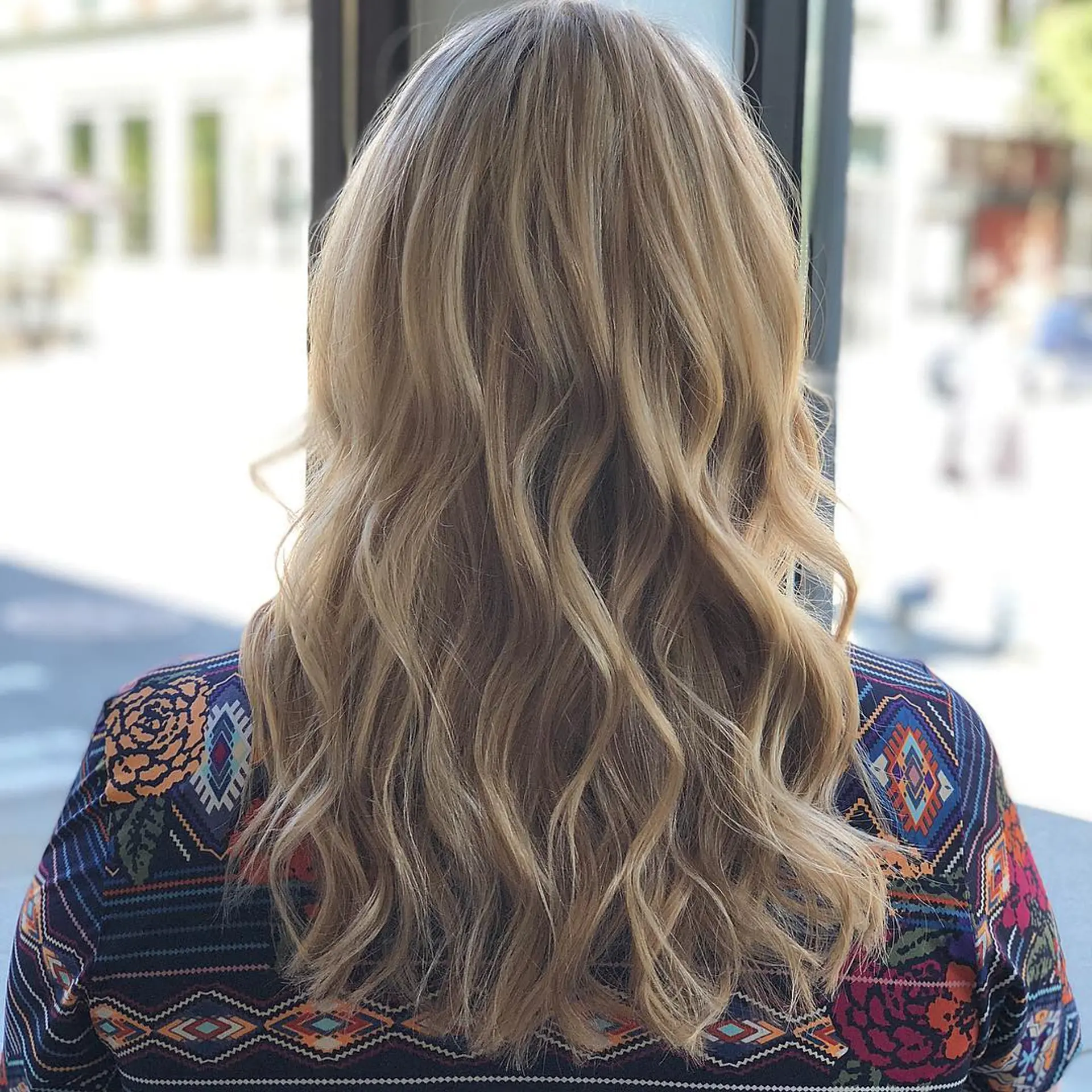 Mid-back length hair styled in loose, natural waves featuring a multi-dimensional blonde balayage. 1