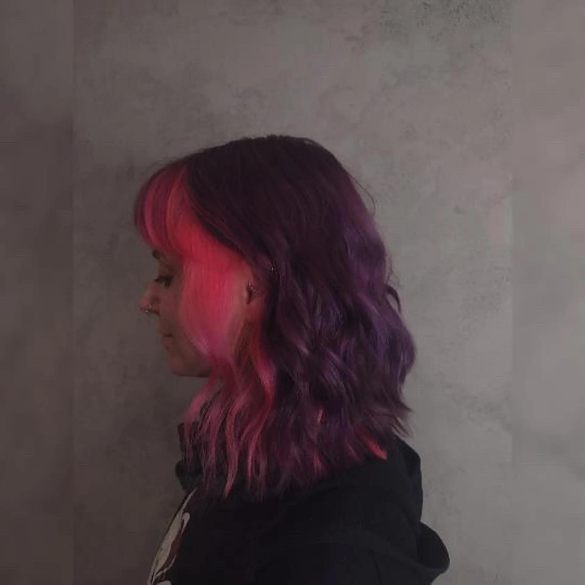 A wavy shoulder-length lob in a deep plum purple contrasted with vivid hot pink bangs and face-framing money pieces. 1