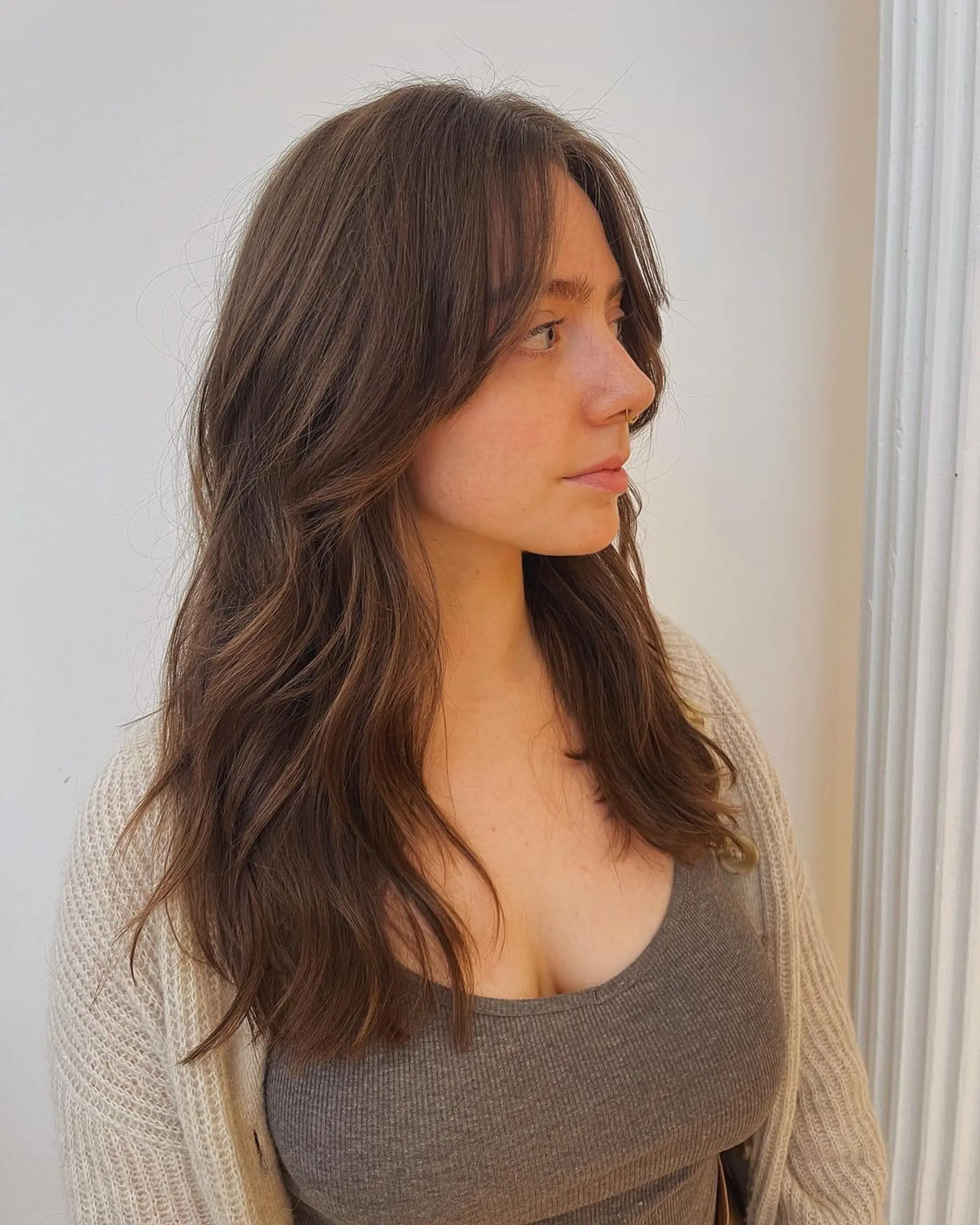 Long wavy hair in a chestnut brown color, featuring a middle part and soft, face-framing layers that create a natural look with casual elegance.