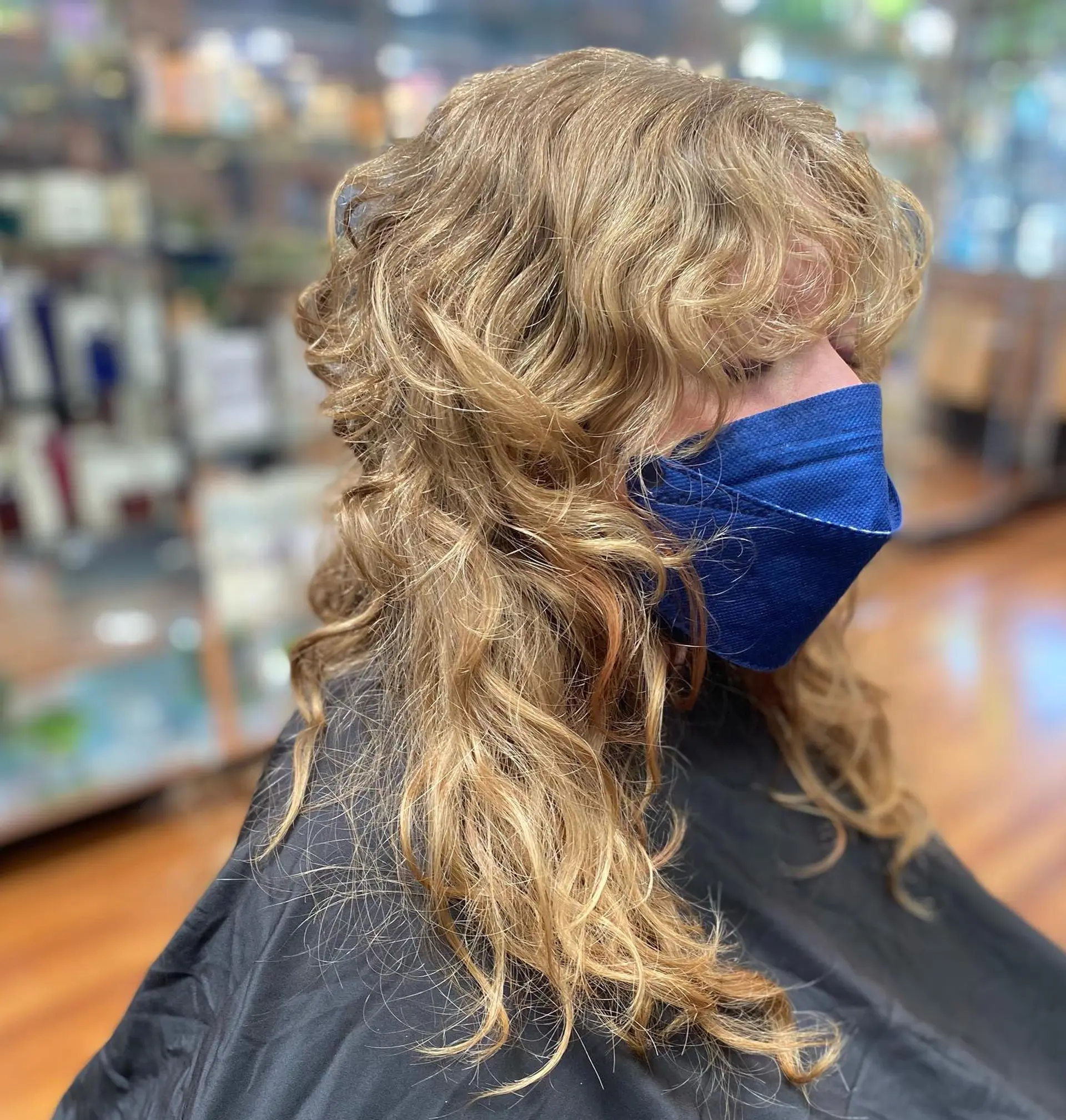 A textured curly shag haircut featuring soft wavy layers and full brow-grazing curly bangs. 1