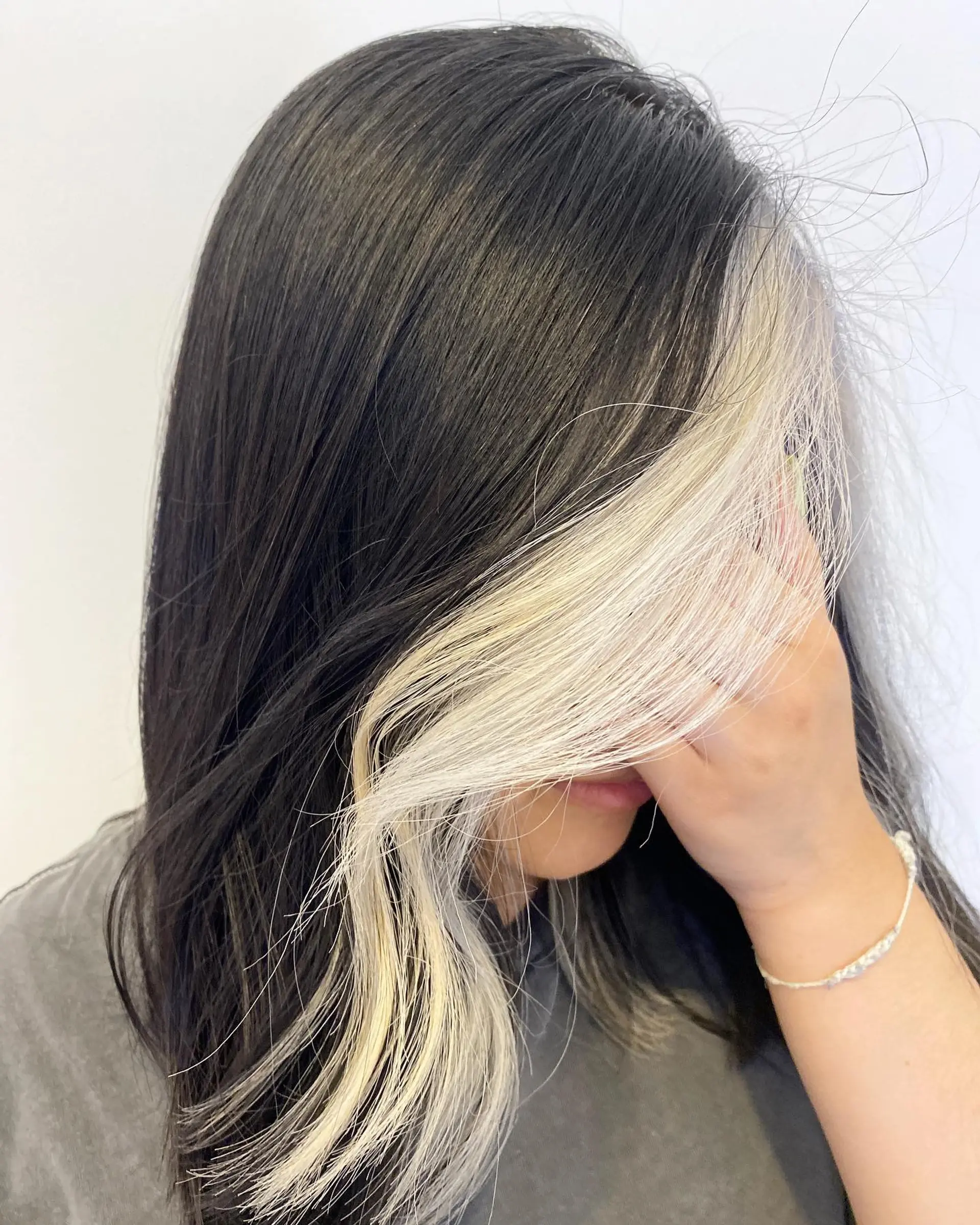 Medium-length dark hair featuring a bold, platinum blonde face-framing money piece. 1