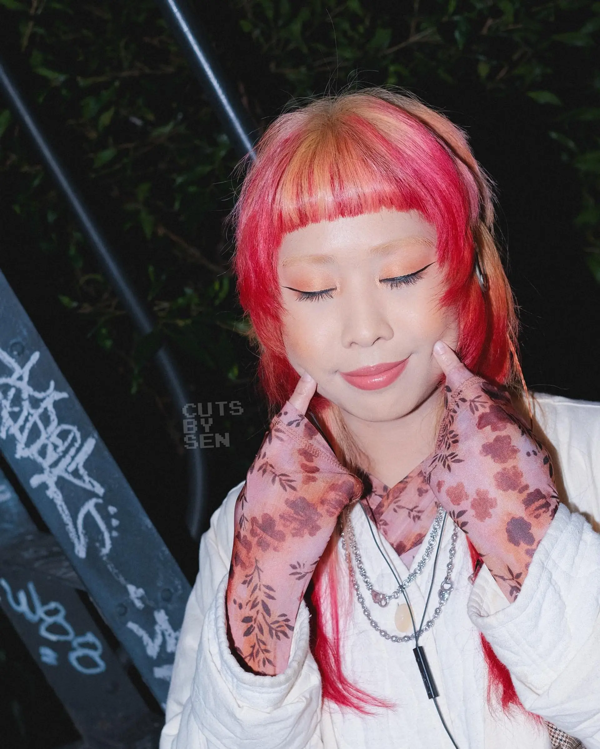 A modern, creative take on the hime cut featuring blunt micro bangs, disconnected cheek-framing steps, and pops of vivid red, pink, and peach color. 1