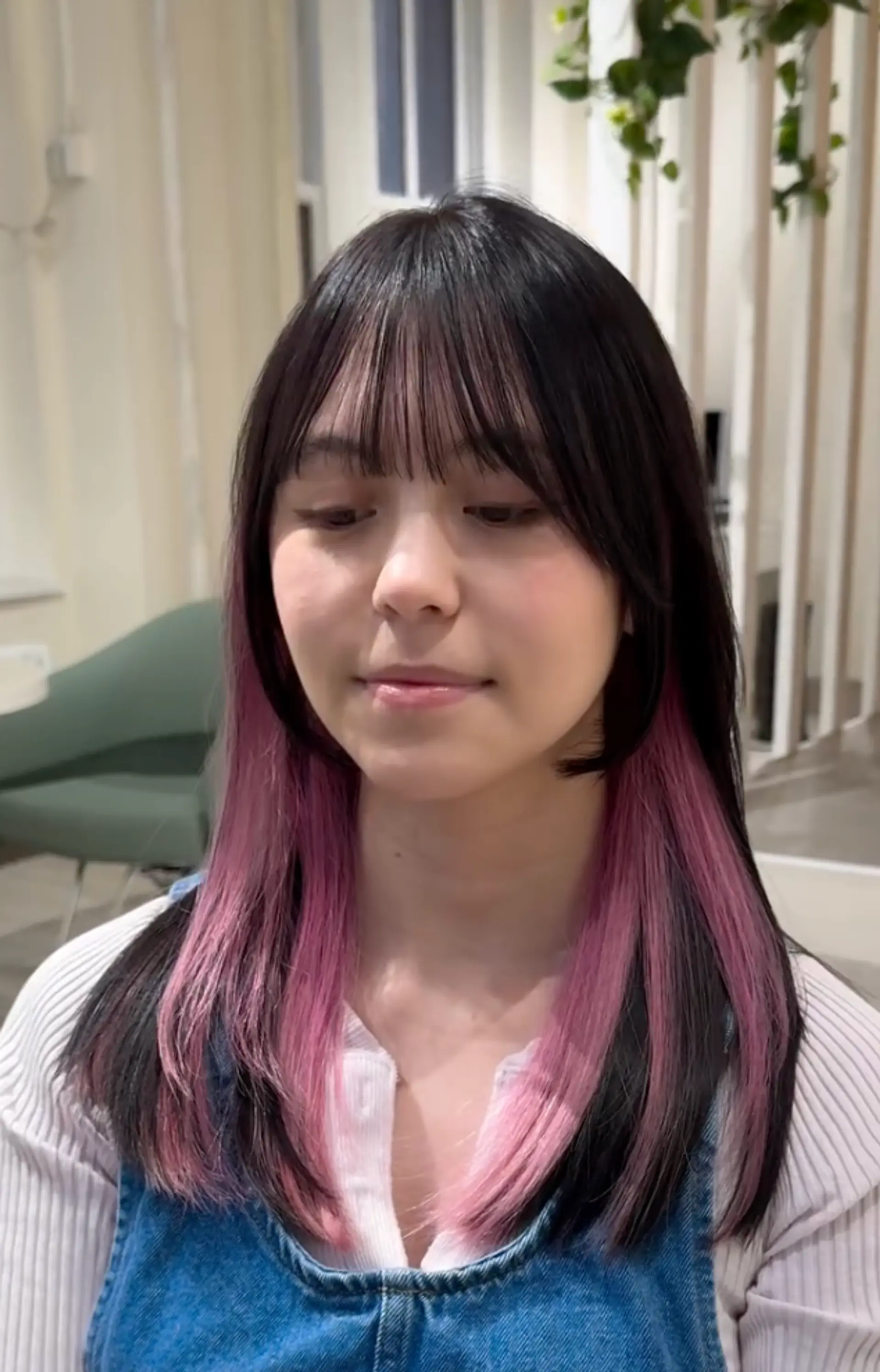 Medium-length straight hair with black roots transitioning to pink ombre ends, blunt bangs, and layered styling.
 1