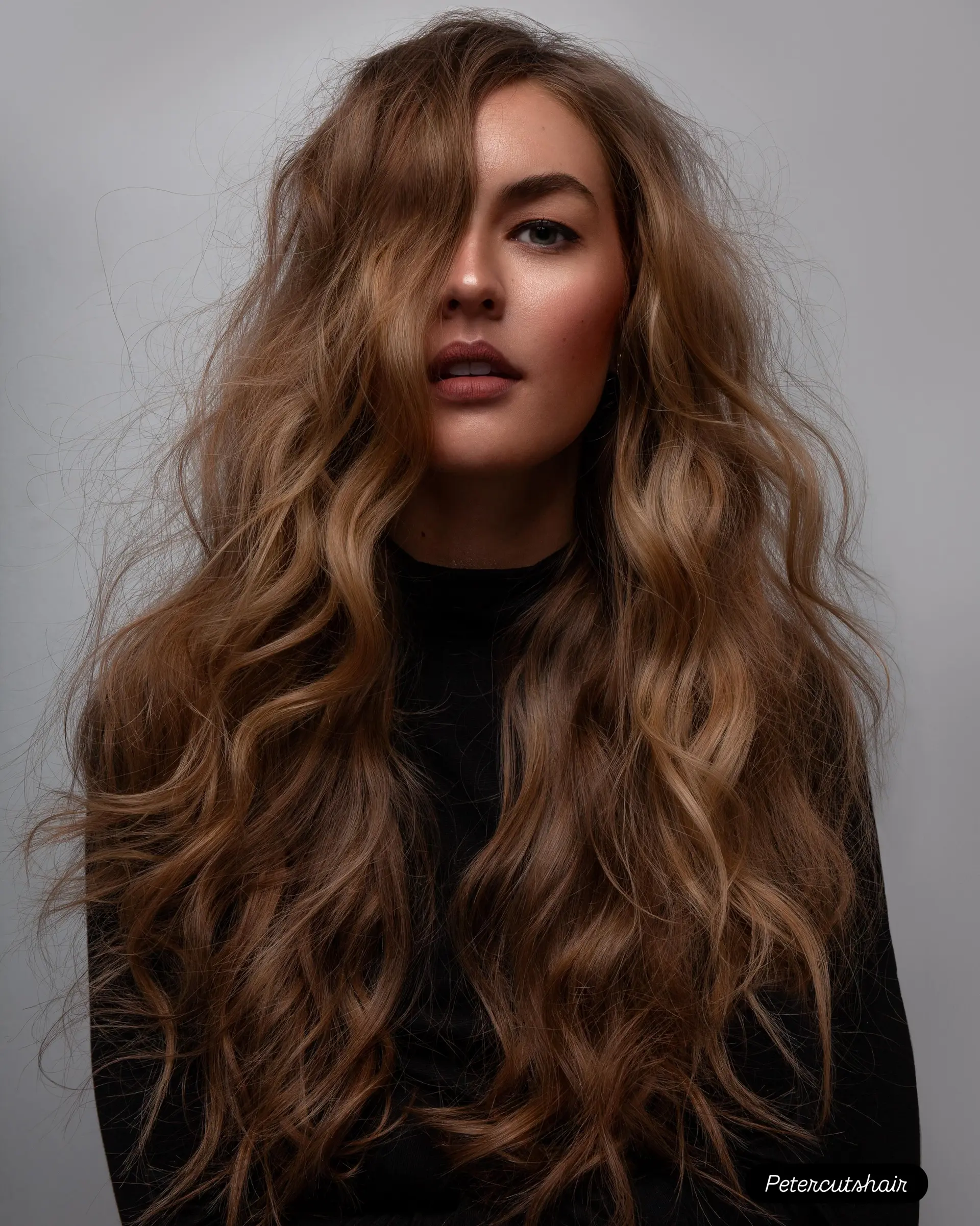 Voluminous long hair styled into tousled, textured waves with a soft side-swept finish. 1