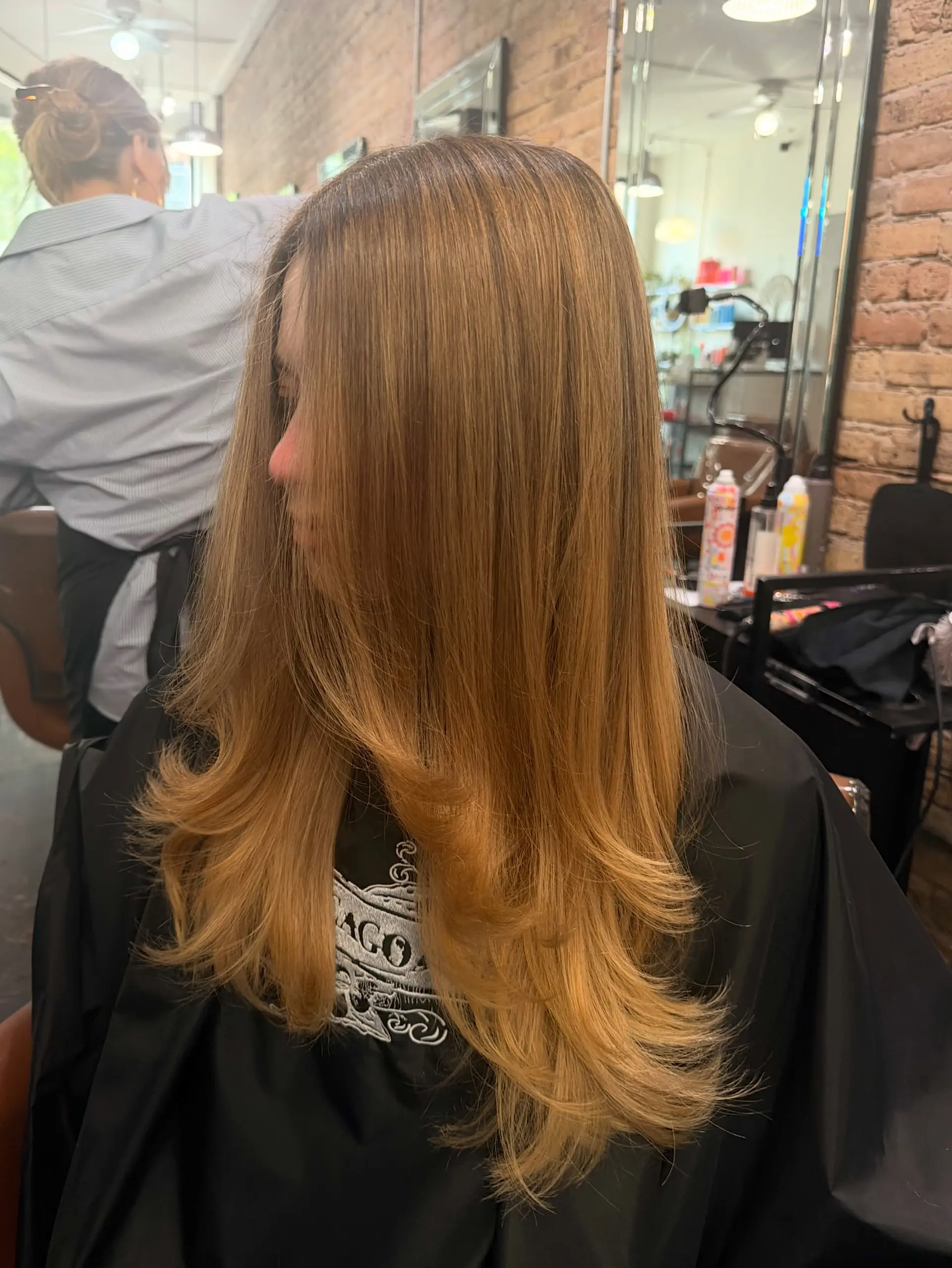 Long warm golden blonde hair cut in smooth cascading layers with flipped-up ends from a round-brush blowout. 1