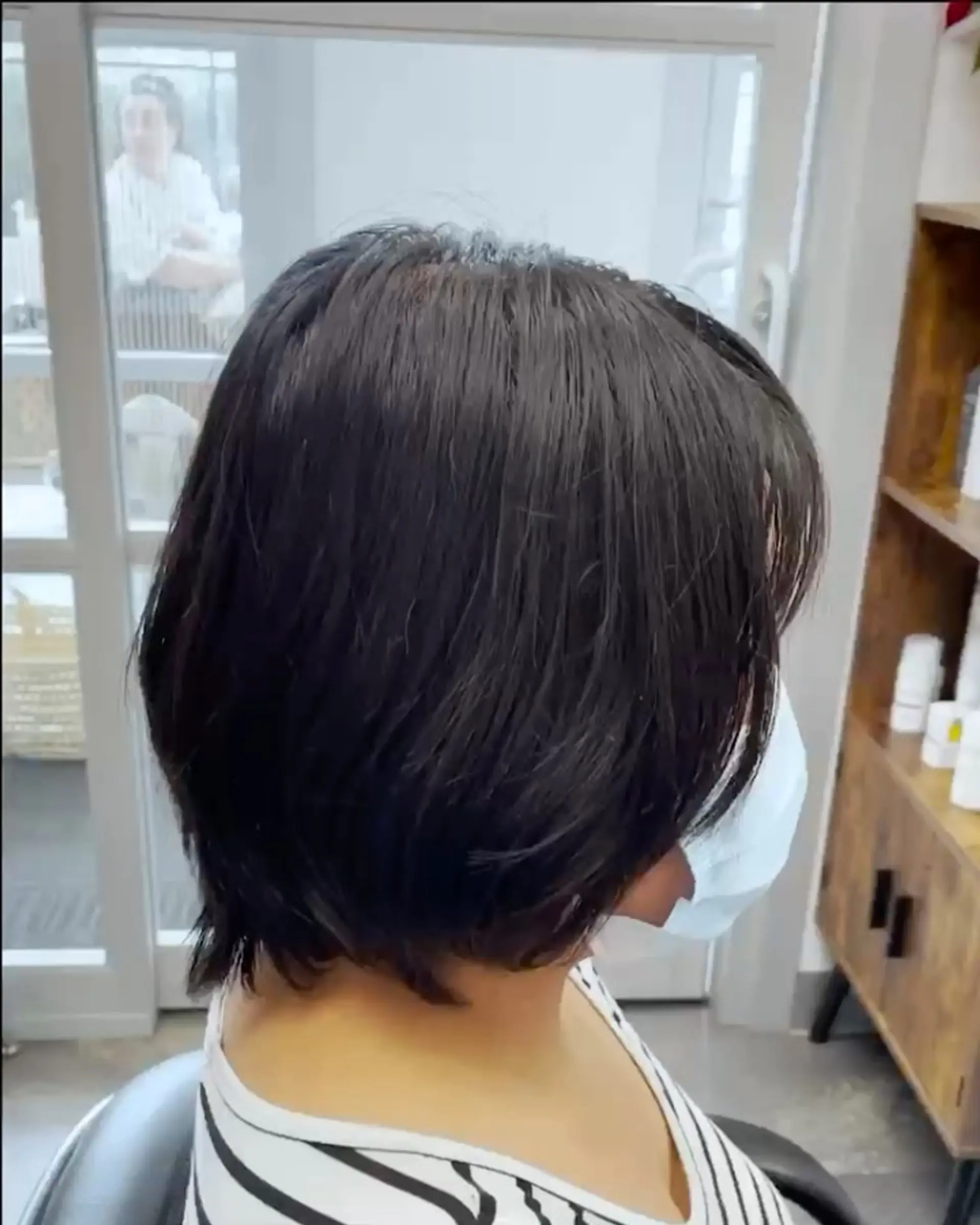 A textured, short dark brown layered bob cut tapering smoothly around the nape. 1