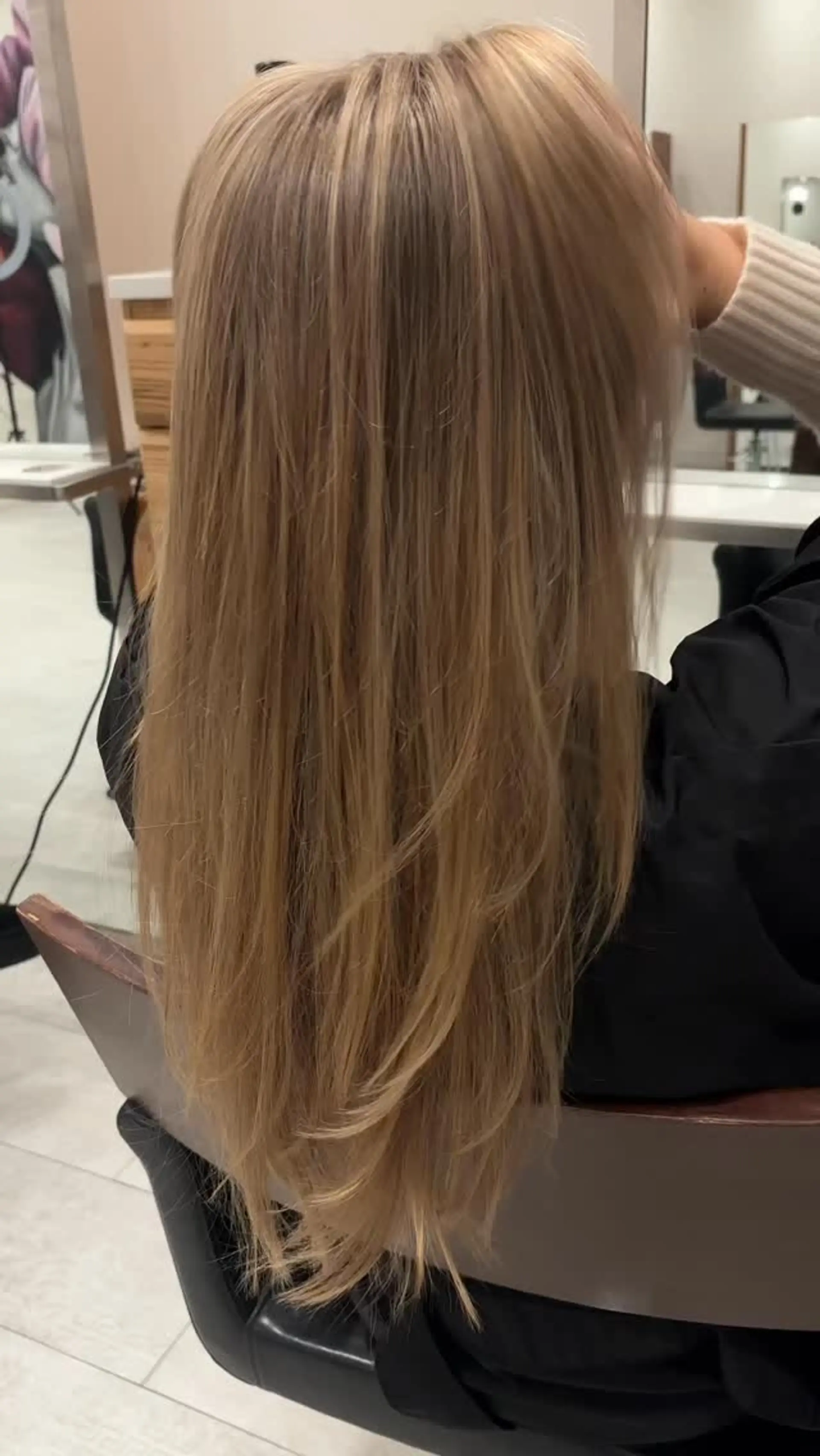 Straight, long hair featuring a warm dimensional teddy bear bronde tone with delicate long layering at the ends. 1