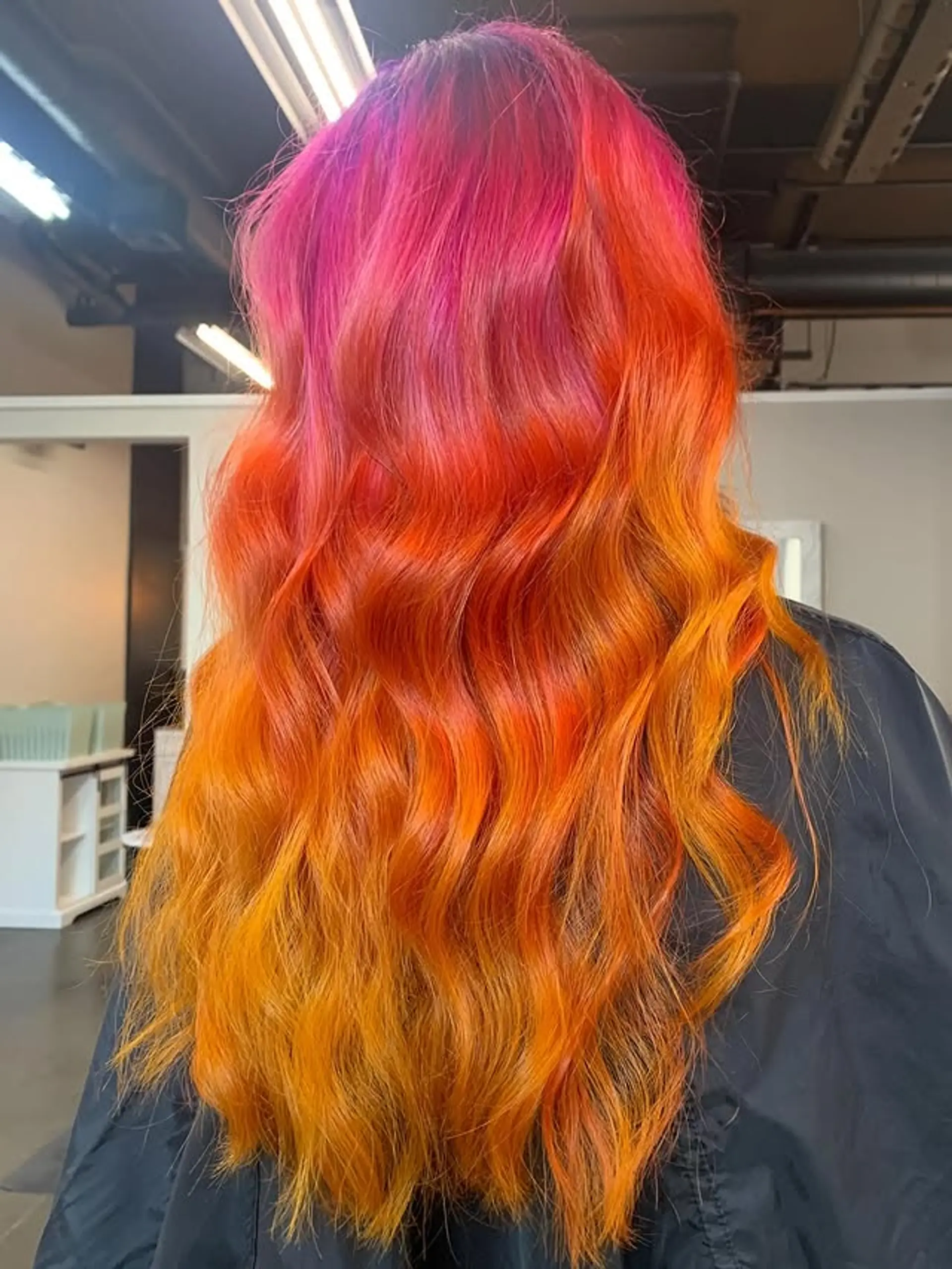 A vibrant, long wavy hairstyle featuring a sunset ombre color melt. 1