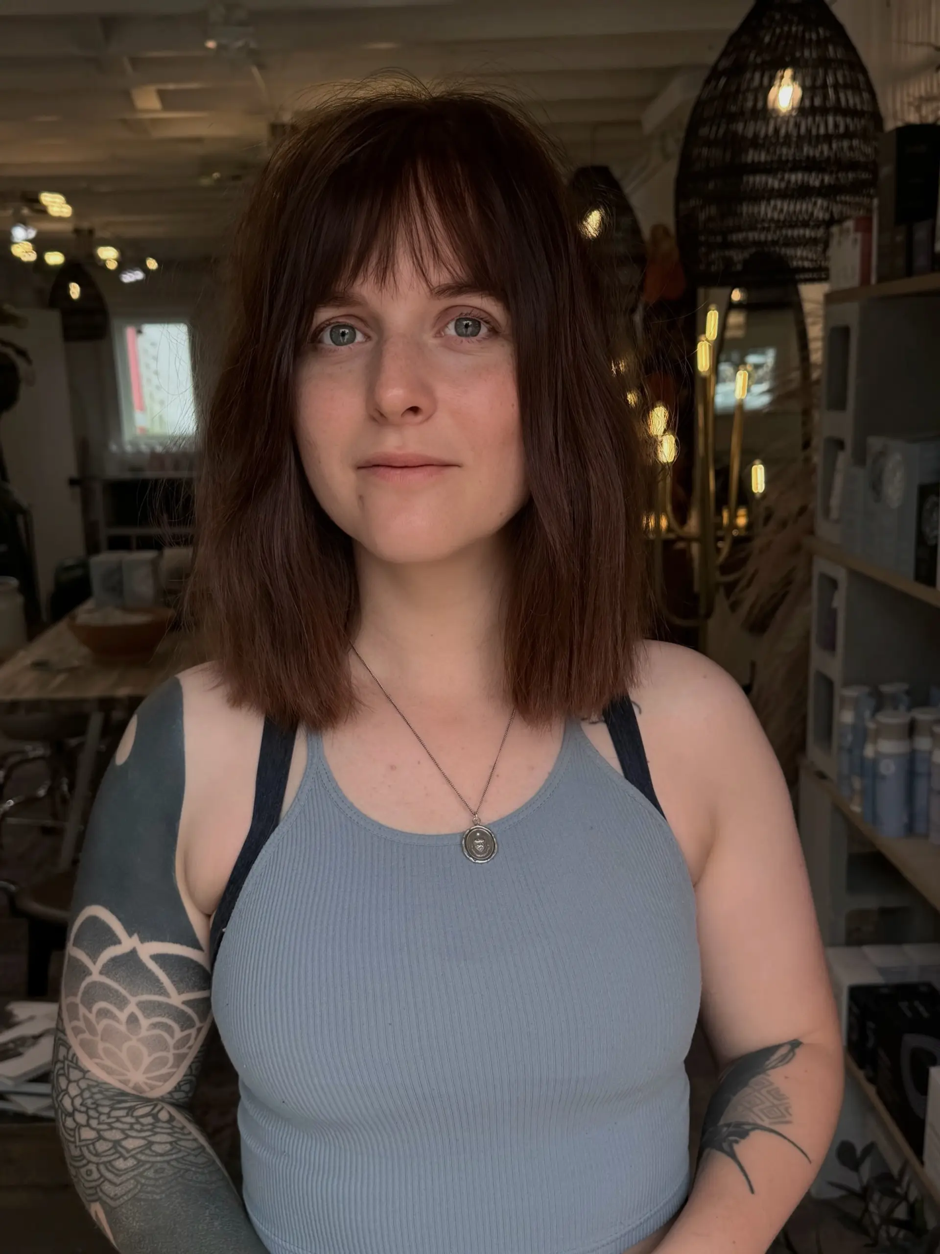 A collarbone-length blunt lob cut styled straight with soft, textured full bangs. 1