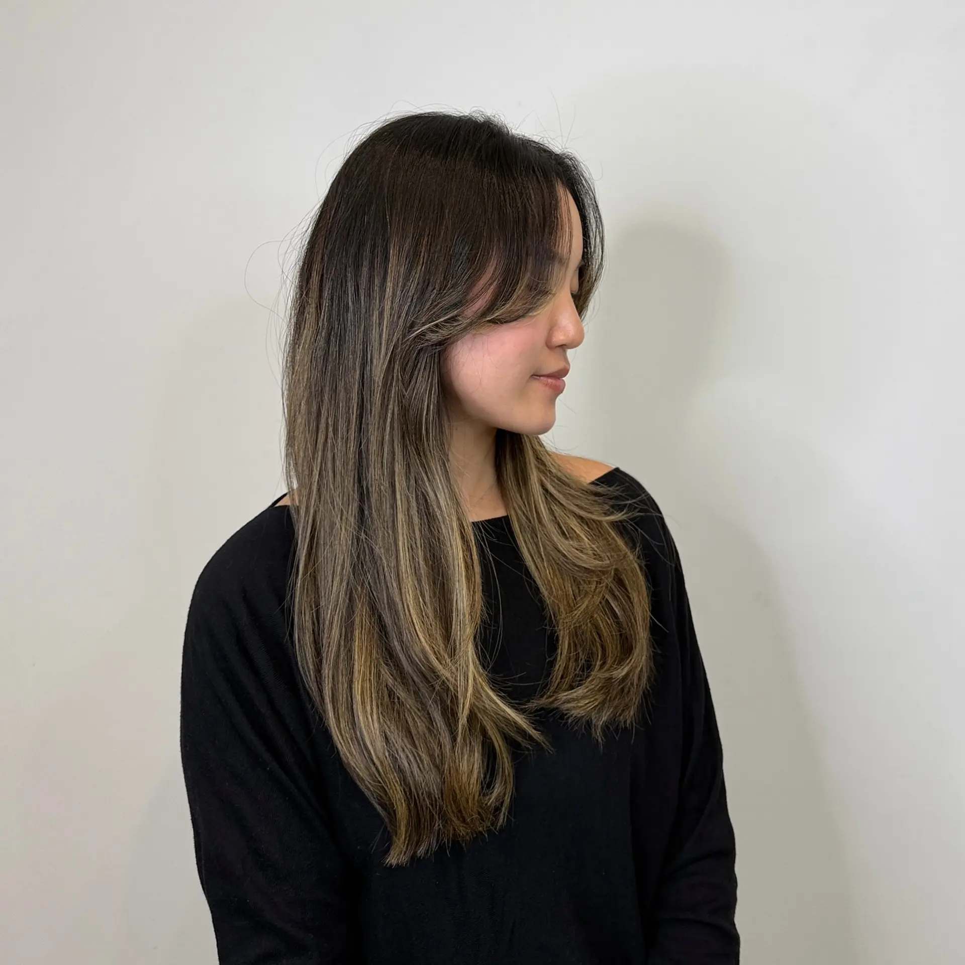 Long layered hair with face-framing curtain bangs and blended light brown highlights. 1