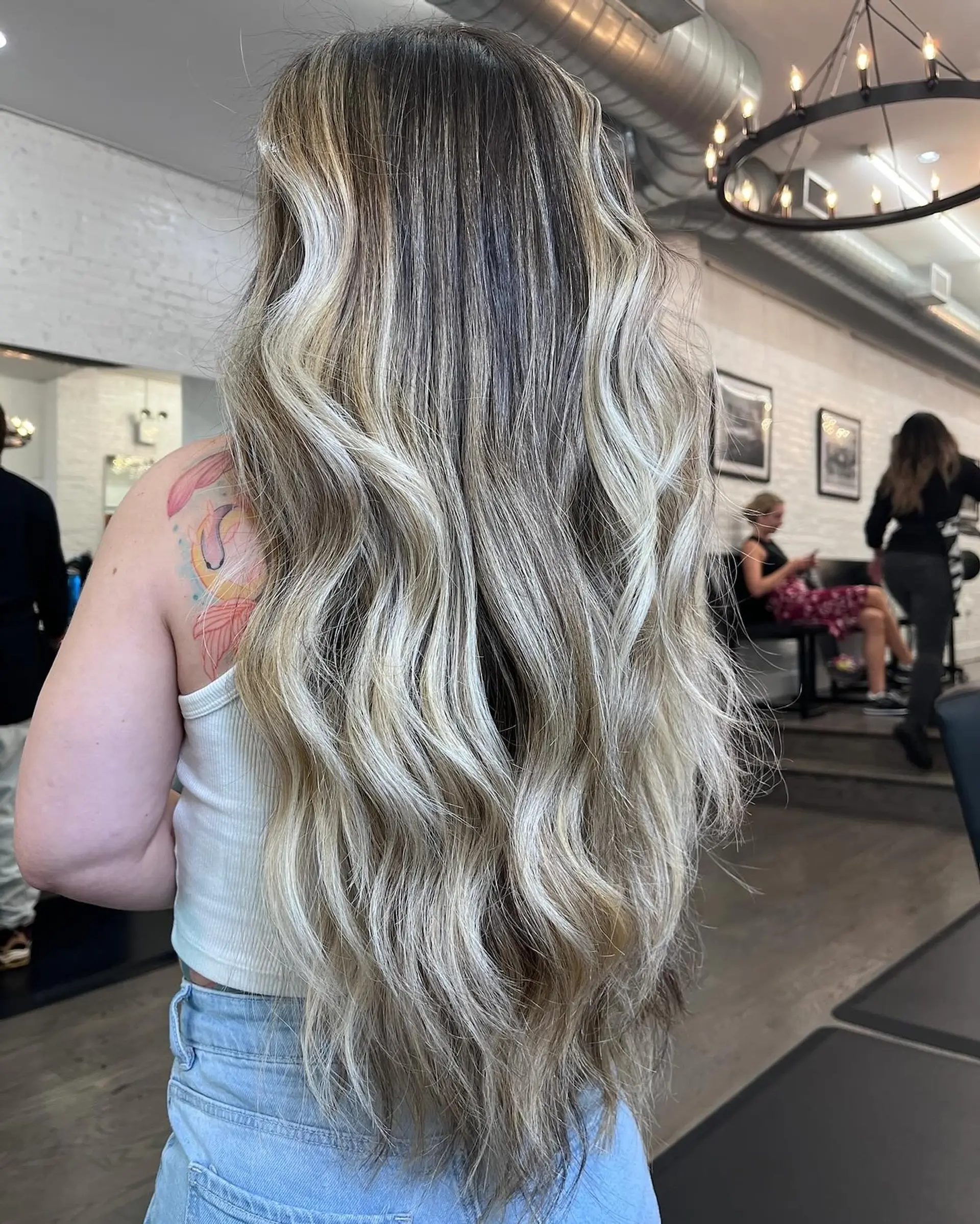 Extra-long layered hair featuring high-contrast dimensional blonde highlights styled into soft, flowing waves. 1