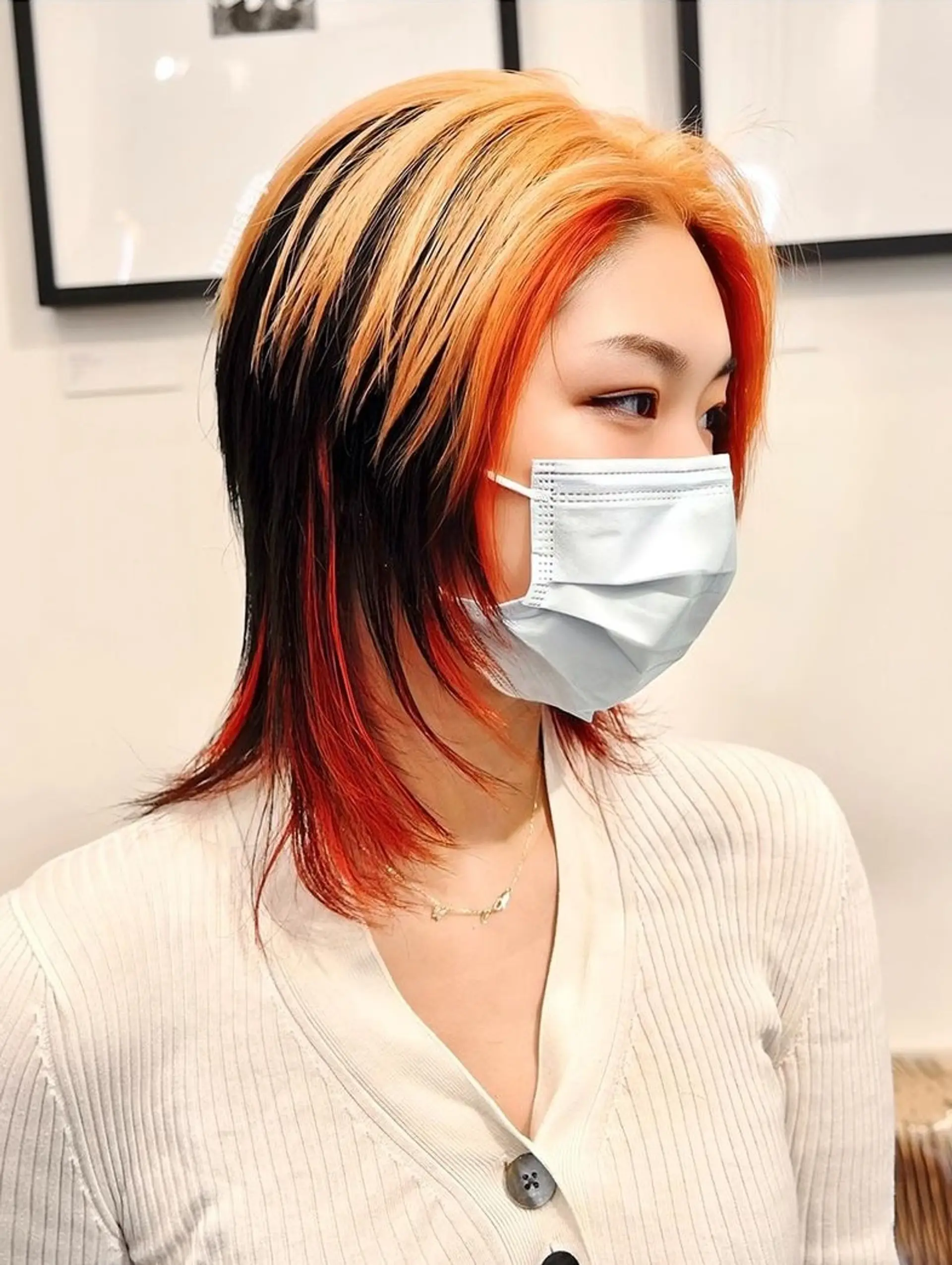 Medium-length, straight hair in a layered cut with a blonde and orange ombre on the outer layer and a black underlayer. 2