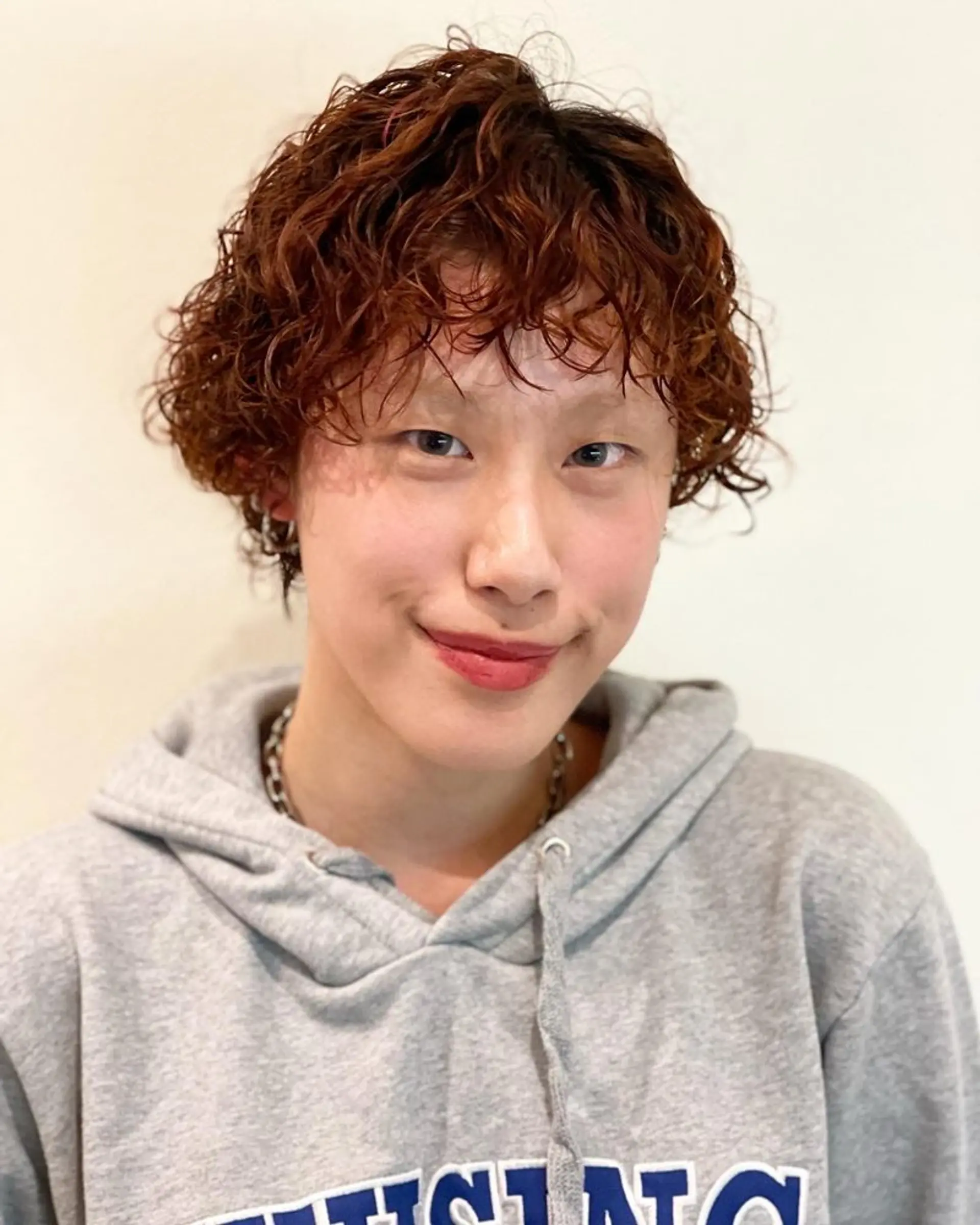 A short pixie cut featuring tight, defined curls with cropped layers. 1