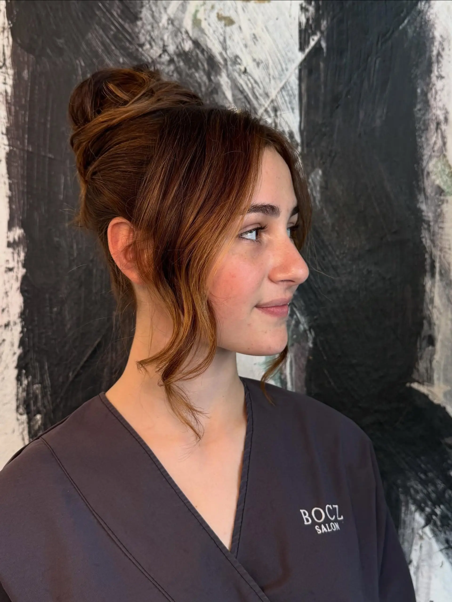 A polished formal updo gathered high on the crown with soft, wavy face-framing tendrils. 1