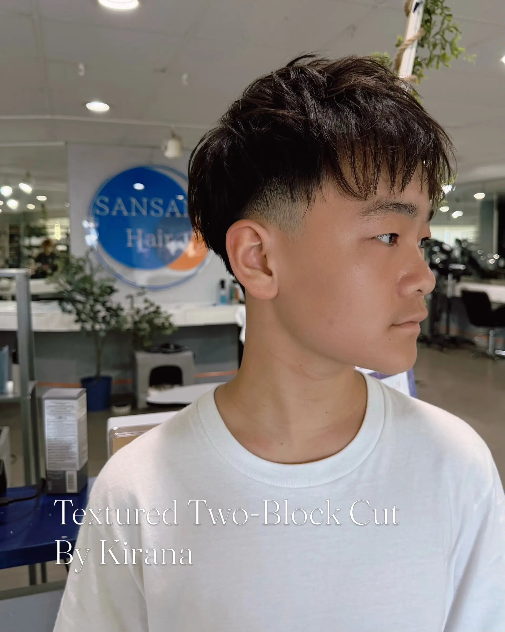 A modern two-block haircut featuring tapered, faded sides and a textured, layered top styled forward with a piecey fringe. 1