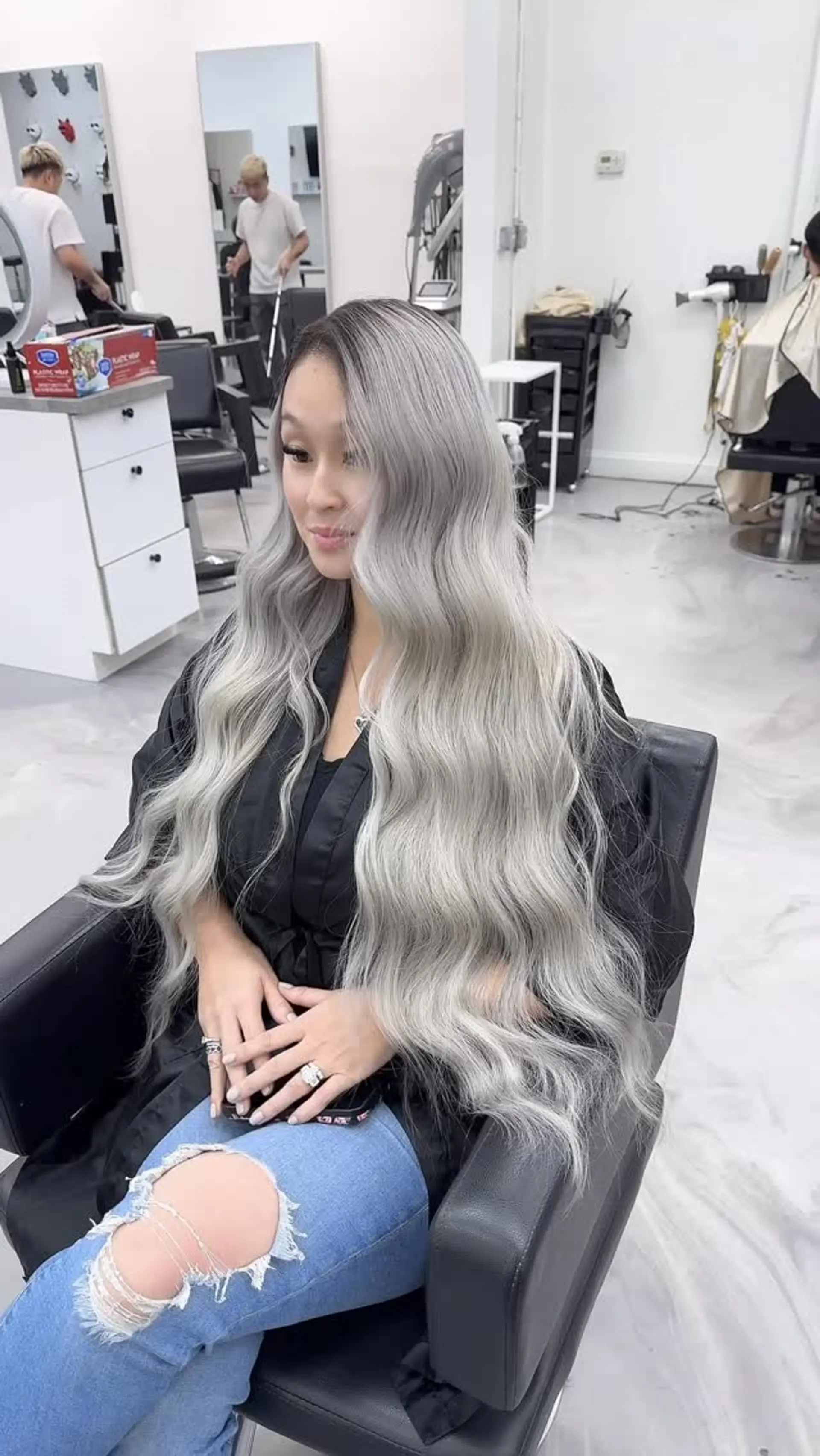 Extra-long cool ash blonde hair with a shadowed dark root, styled into polished, cascading waves. 1
