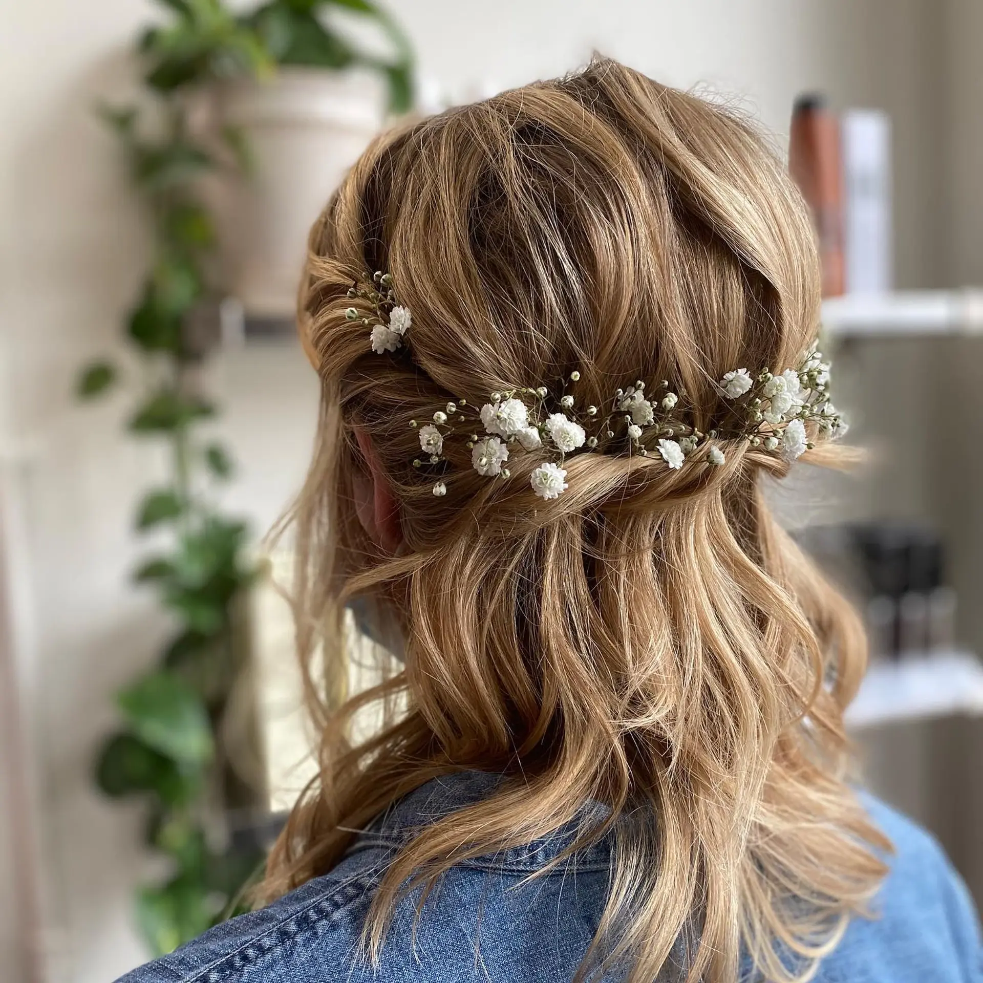 A romantic half-up, half-down hairstyle featuring loose waves, twisted crown sections, and delicate baby's breath tucked across the back. 1