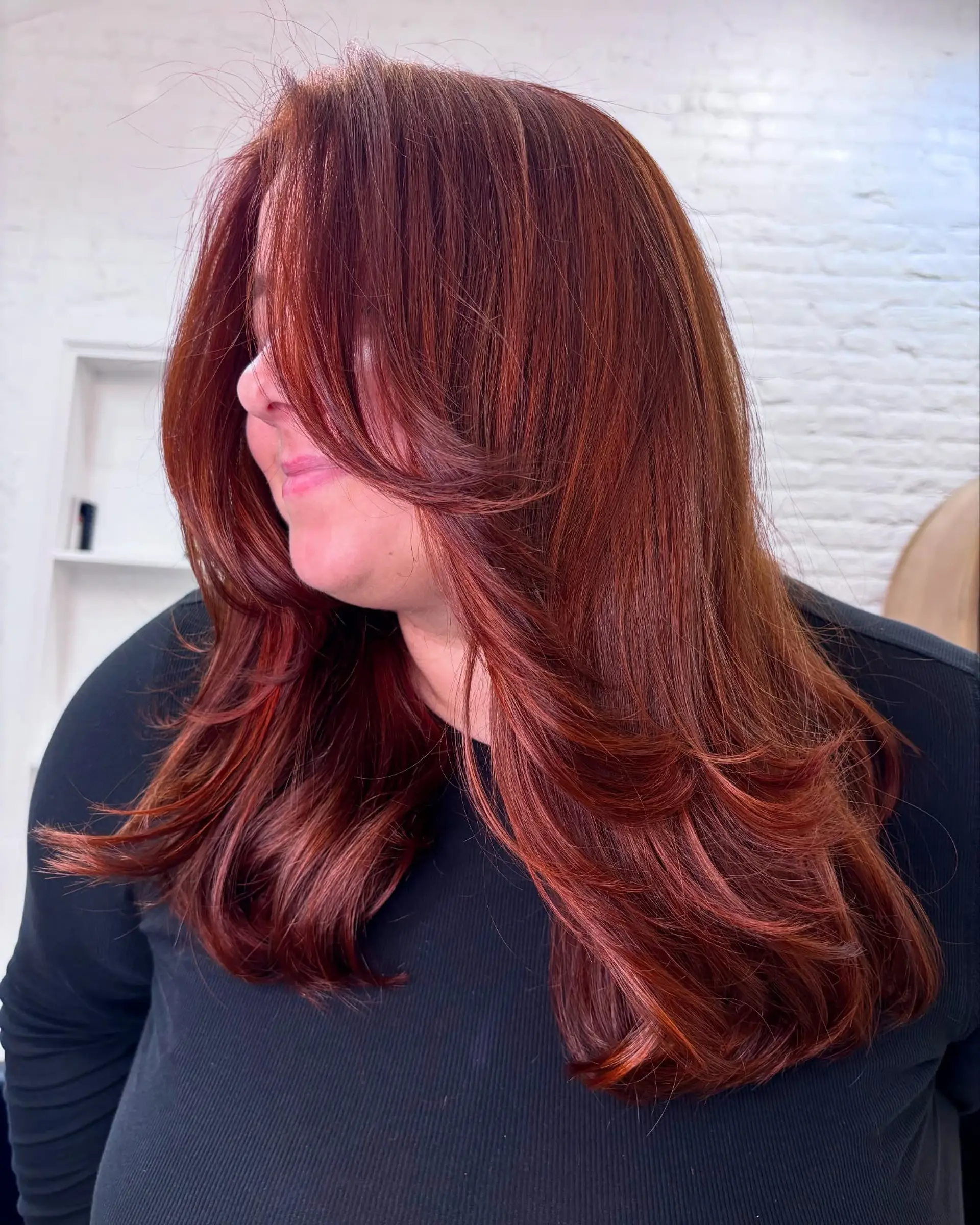 Long, vibrant auburn-red hair styled with face-framing layers and soft, curled-under ends. 1