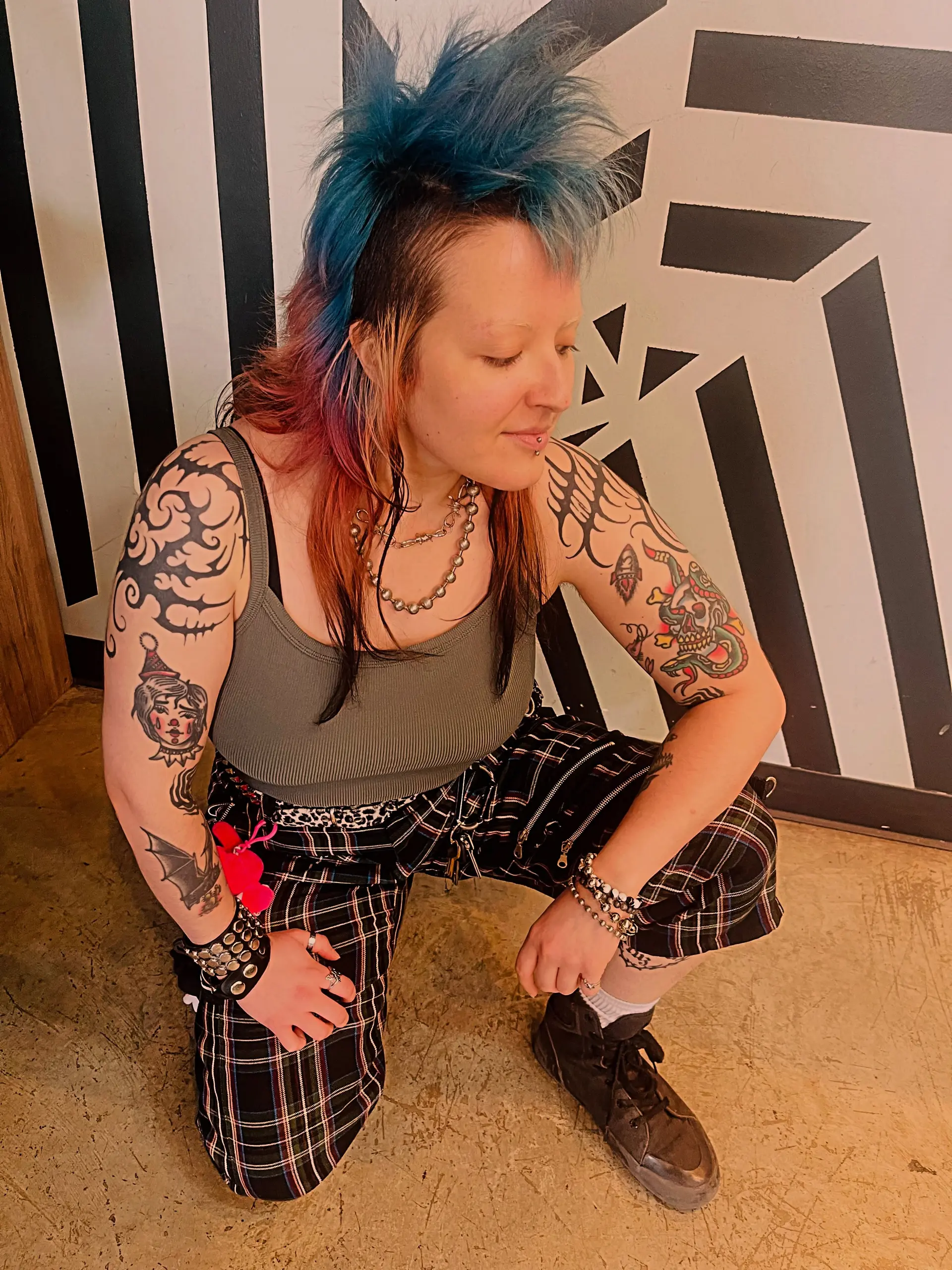 A bold punk rock mullet featuring buzzed sides, an upright spiky blue crest, and blended pink and blonde lengths resting on the shoulders. 1