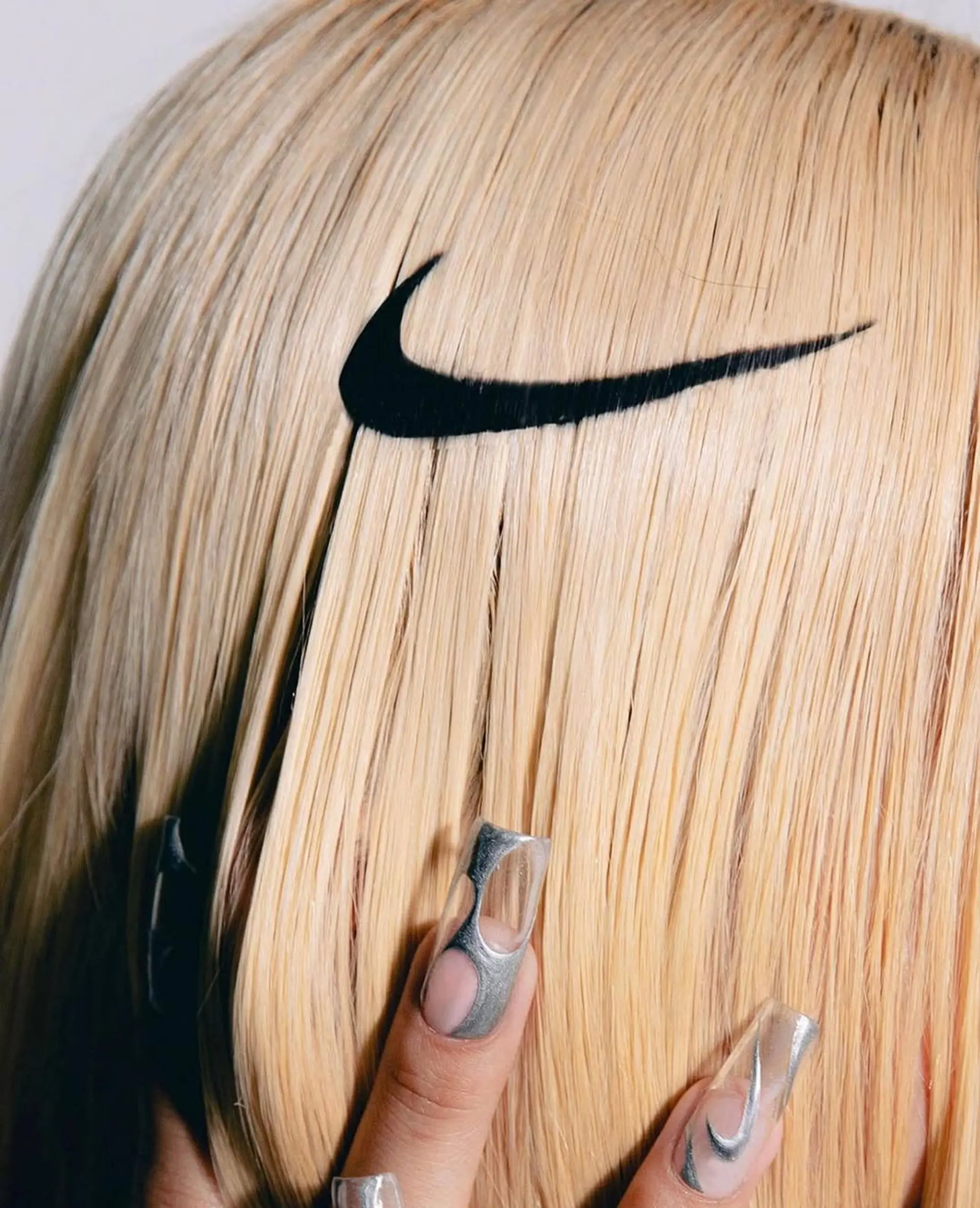 A sleek, medium-length platinum blonde hairstyle featuring a graphic black swoosh design integrated into the layers. 1
