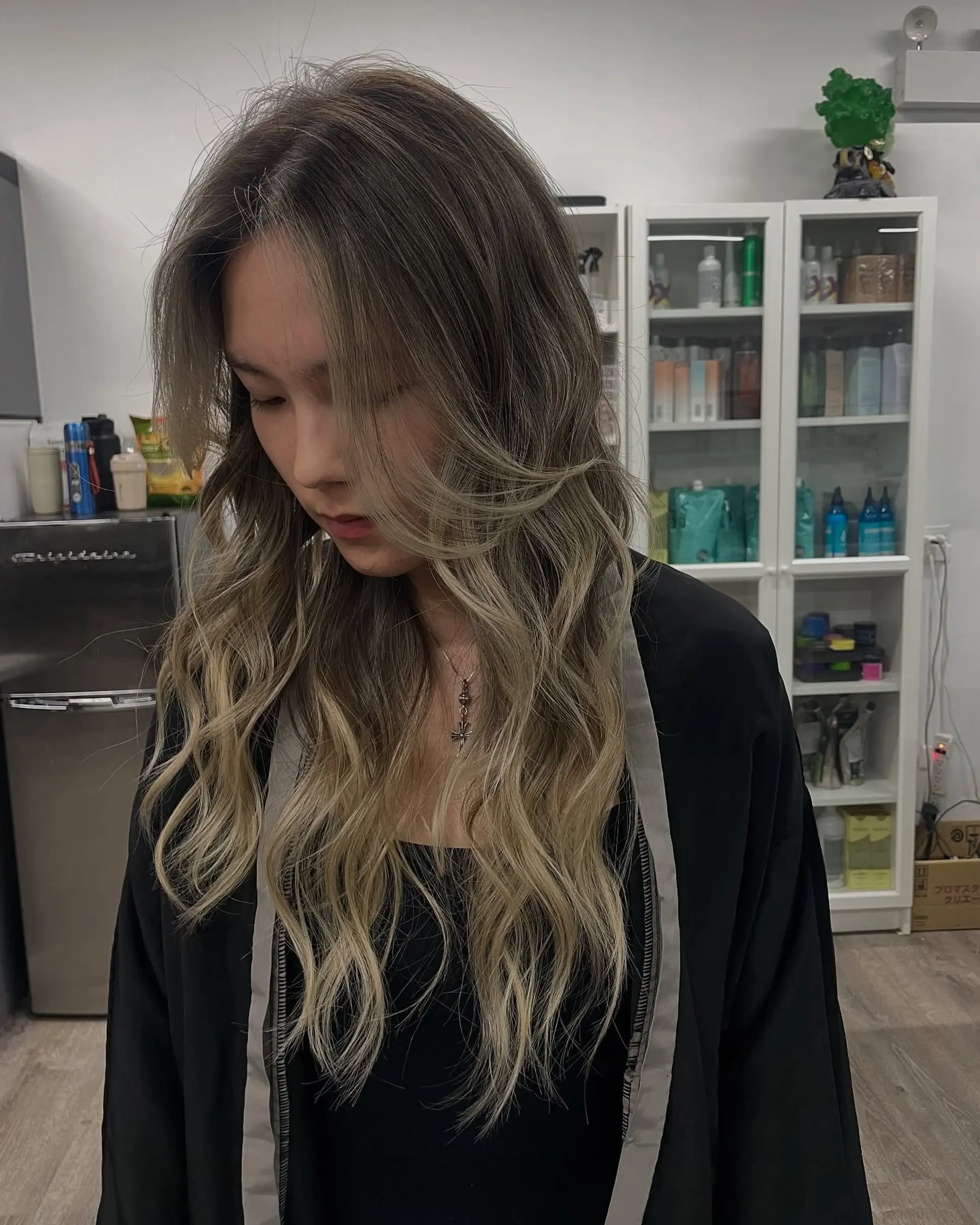 Long, layered wavy hairstyle with face-framing layers and a seamless blend of dark roots into an ash blonde. 1