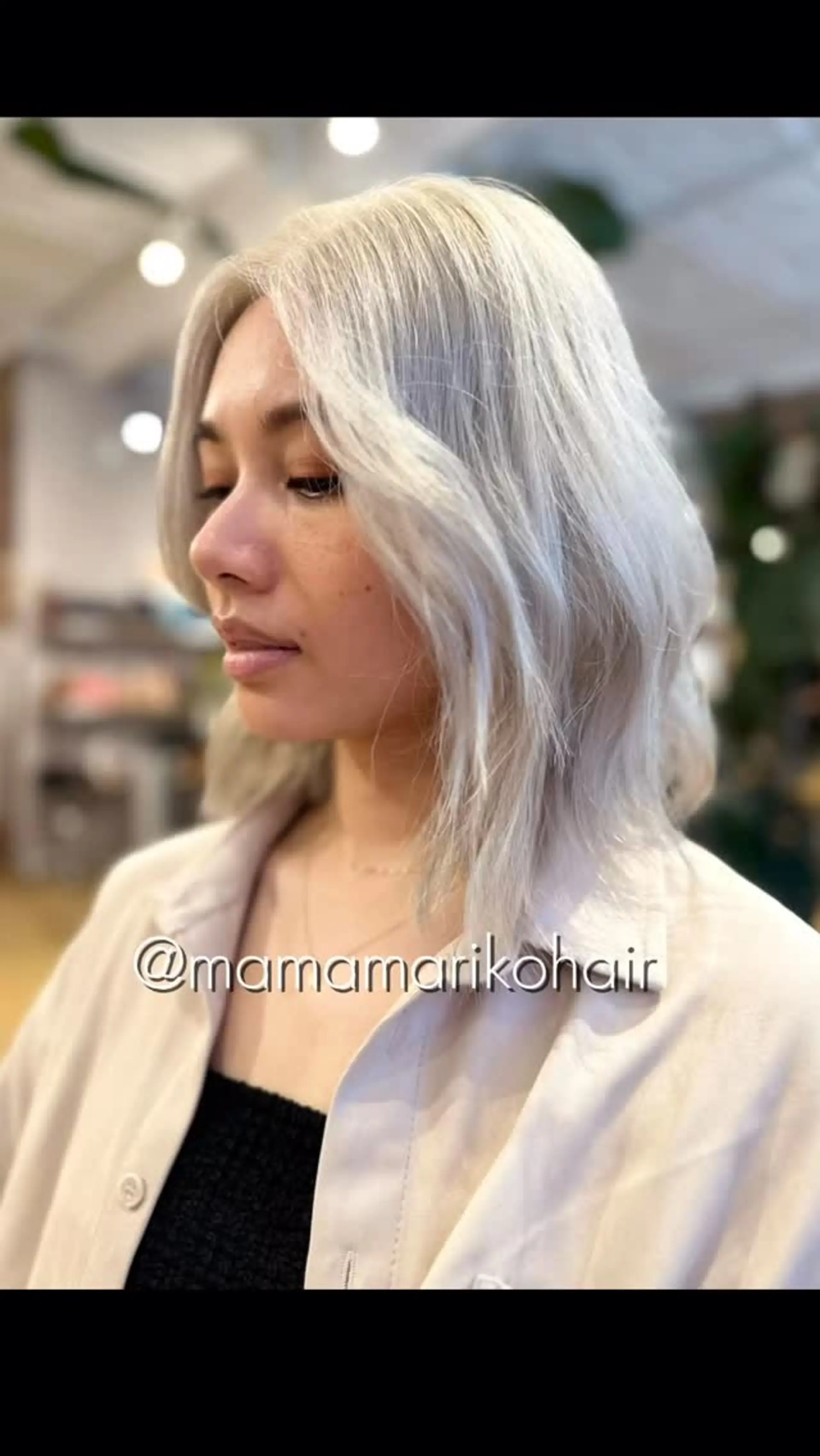 A textured shoulder-length platinum blonde lob styled with soft face-framing waves. 1