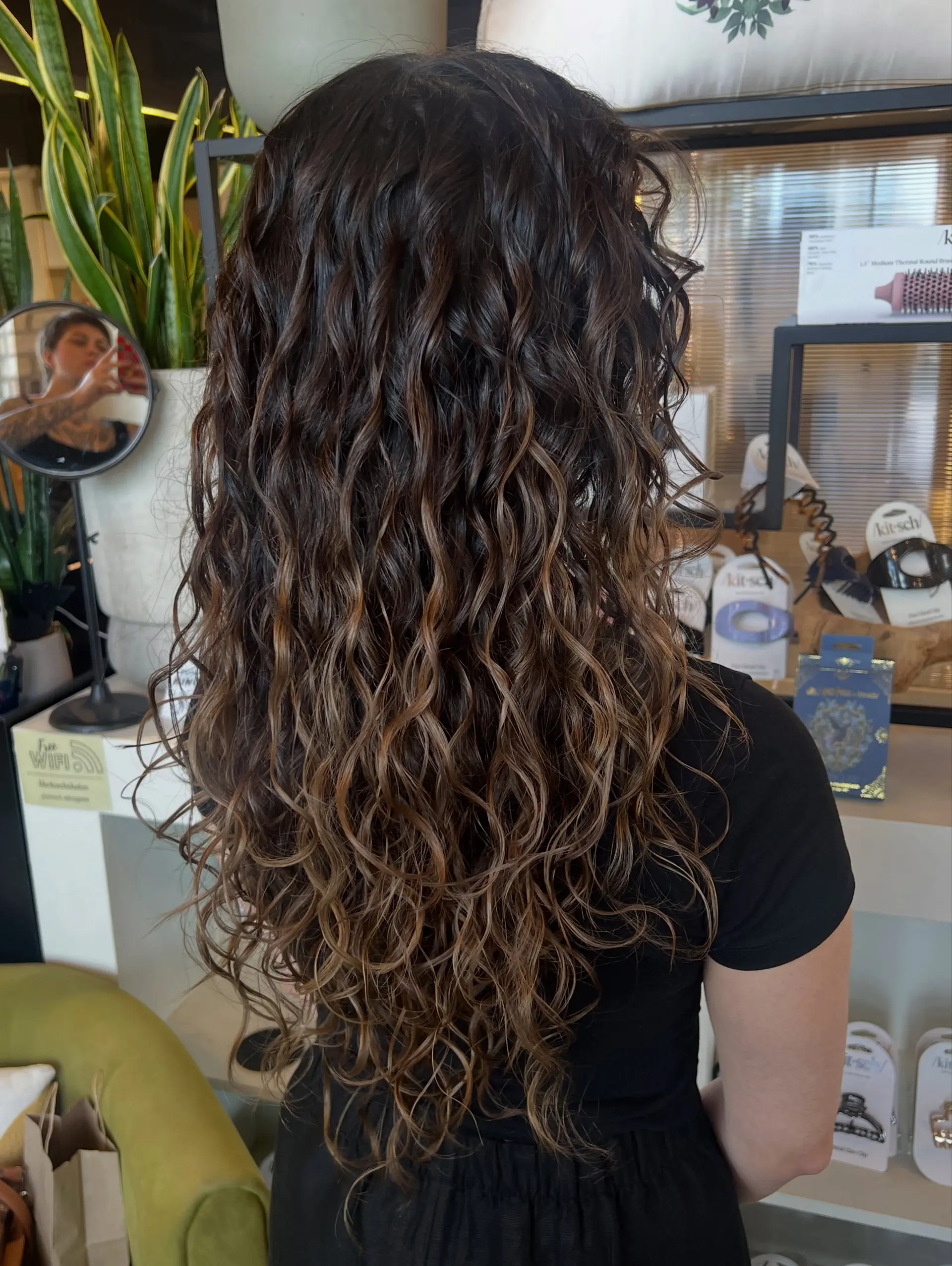 Long naturally textured curly hair styled with defined spiral curls and a seamless reverse balayage dimension. 1