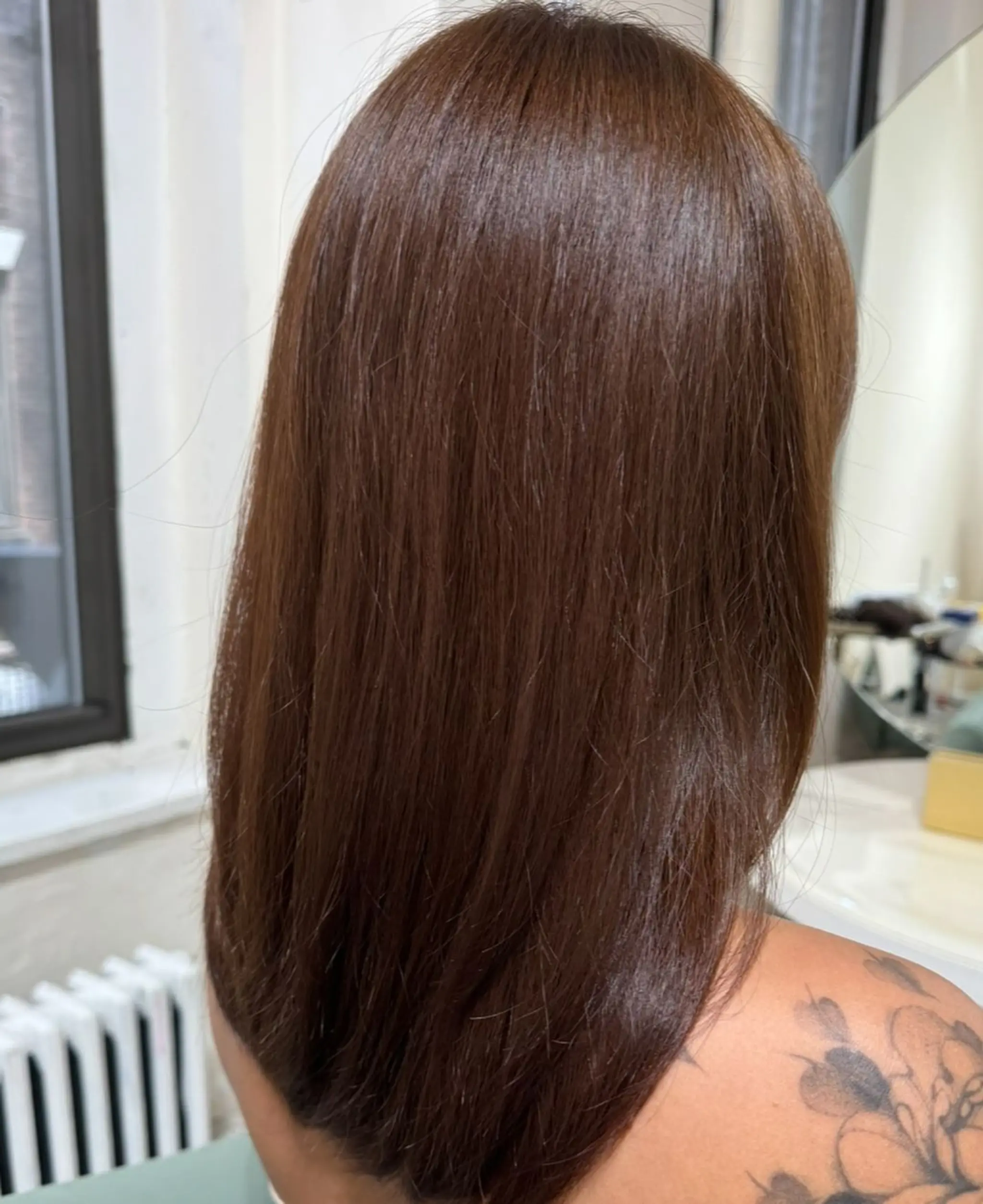 Long and sleek chestnut brown hair with a natural shine. The straight, glossy finish creates a polished and healthy appearance.