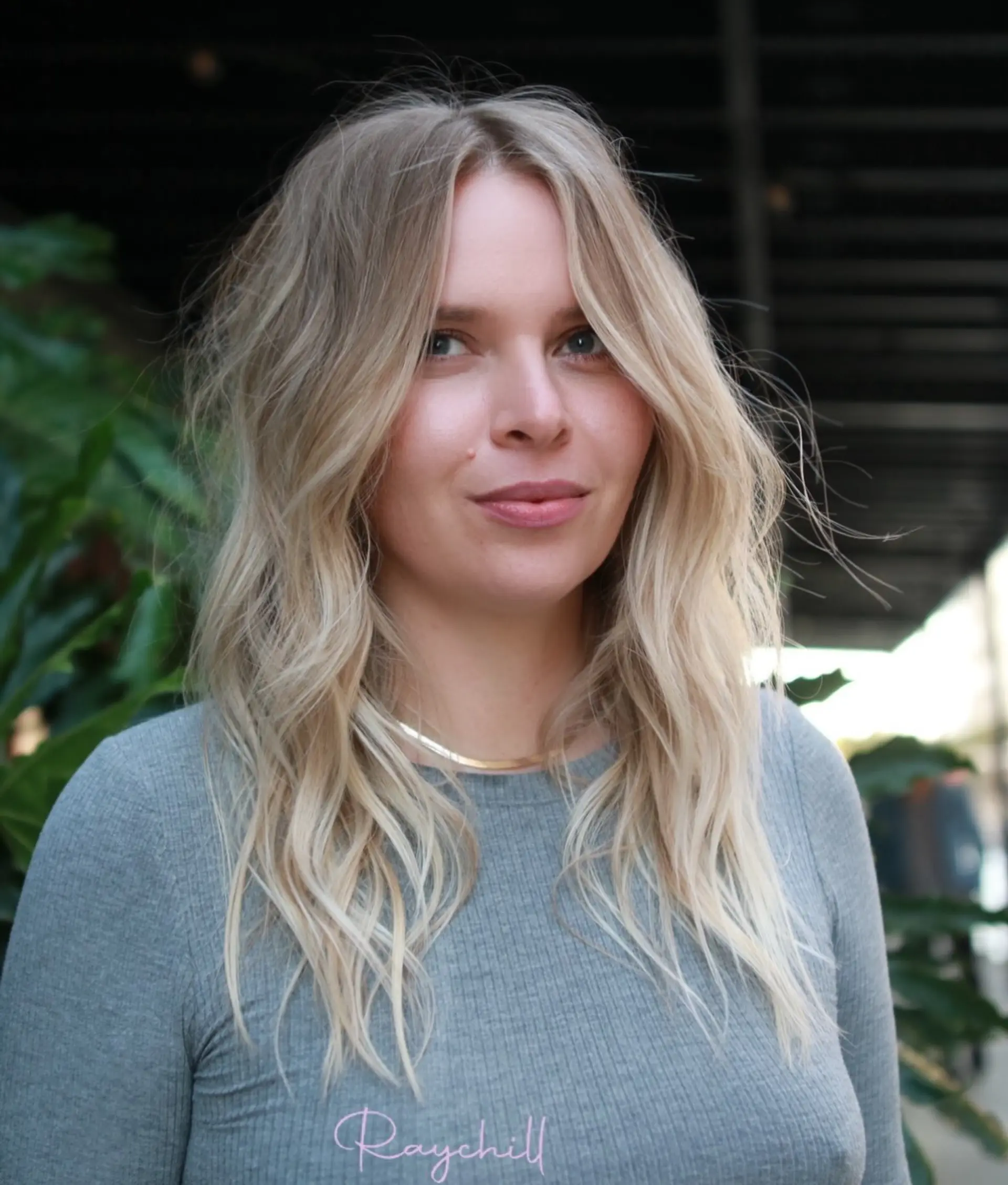 Bright blonde layered hair styled into relaxed, lived-in waves with face-framing fringe pieces. 1