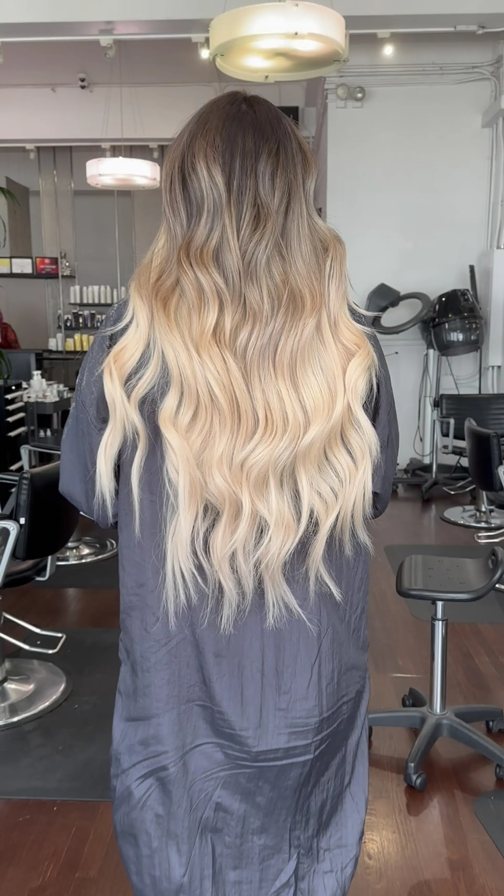 Extra-long hair styled in soft cascading waves with an ash brown shadow root blending into light platinum blonde. 1