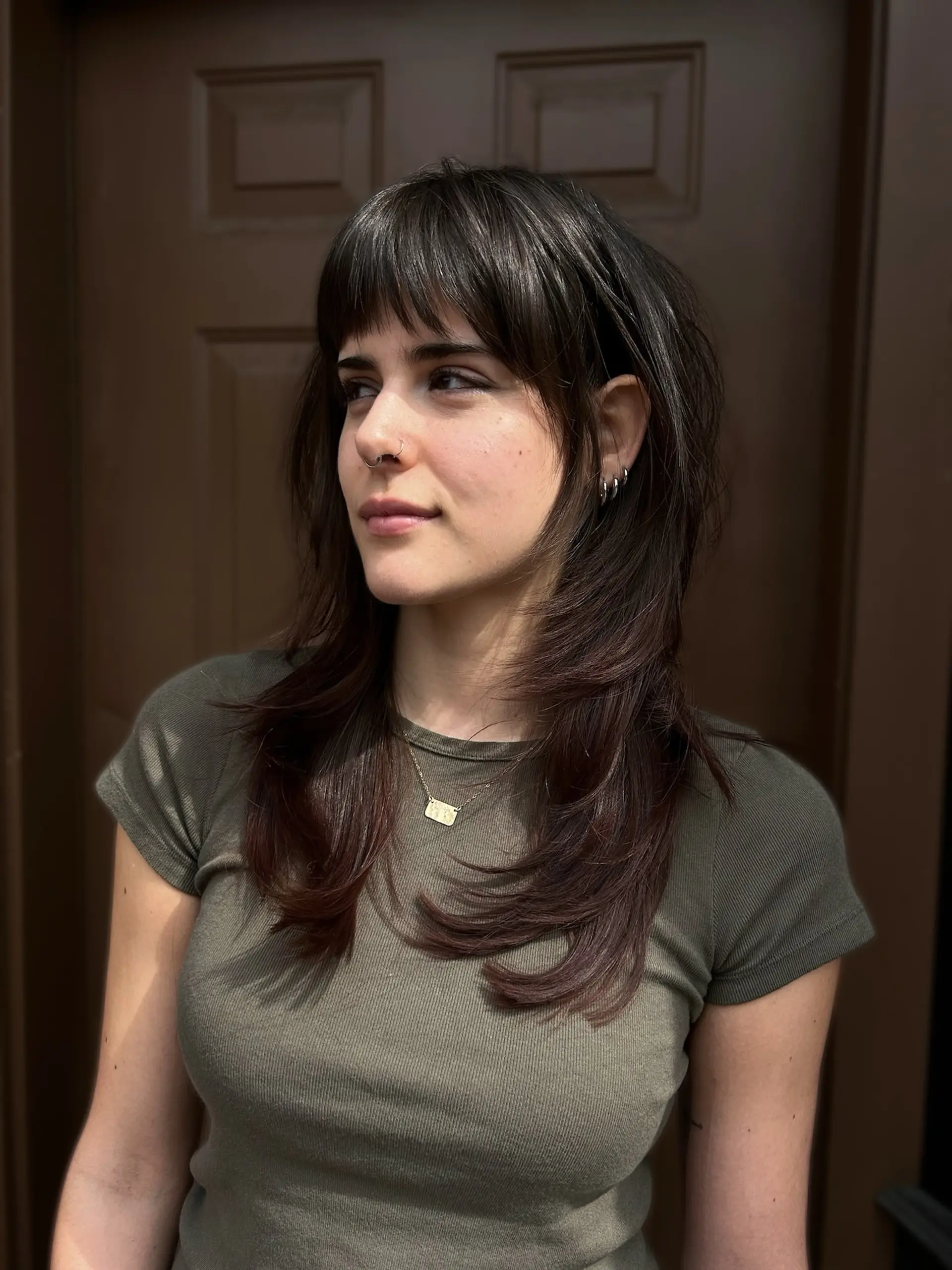 A textured, feathered wolf cut with piecey full bangs and soft, face-framing layers cascading past the collarbone. 1