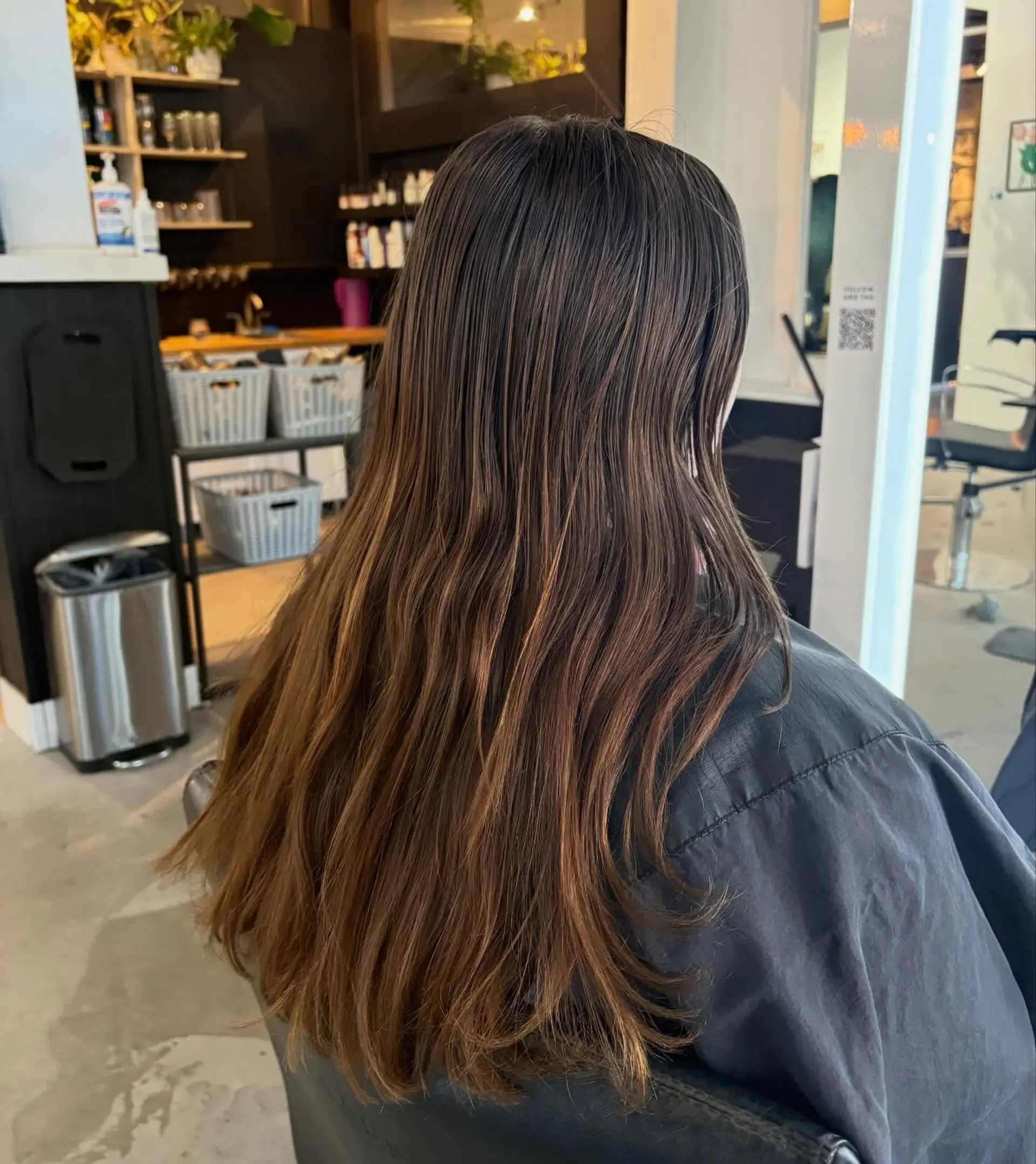 Long dark brown hair featuring soft, cascading layers that taper into warm caramel-toned ends with gentle movement. 1