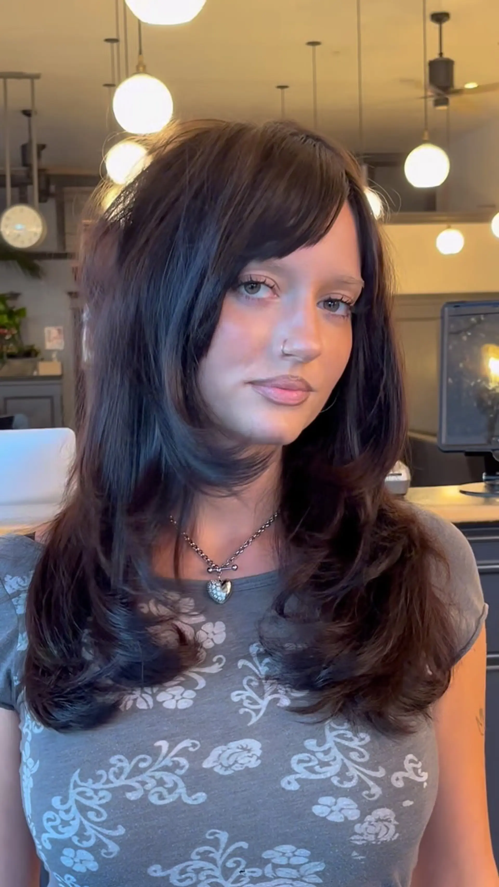 Long dark brown hair cut with tiered face-framing layers, soft flipped ends, and angled side bangs. 1