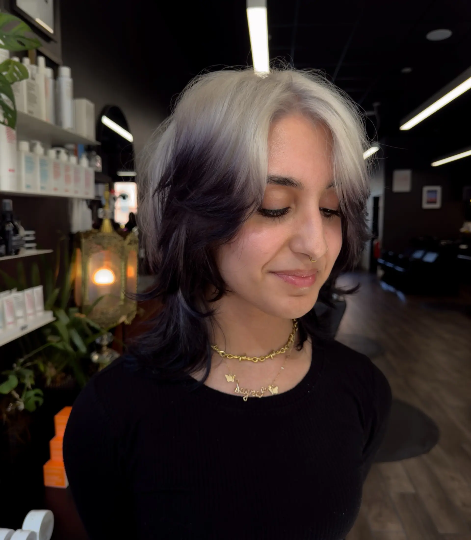A textured medium-length shag cut featuring a striking two-tone contrast with platinum blonde over a deep black base. 1