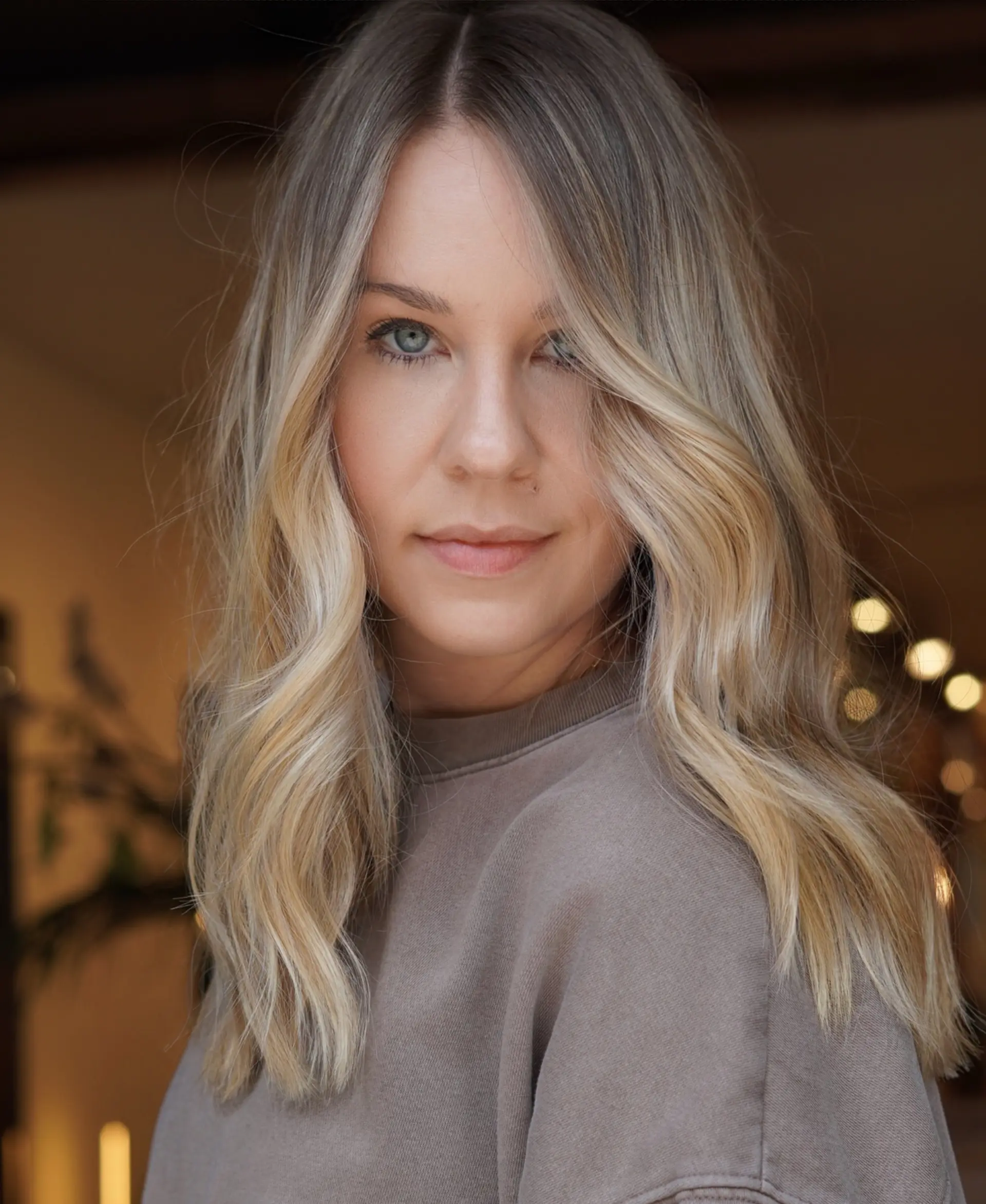 Medium-length dimensional blonde hair styled with soft, loose waves and a central part. 1