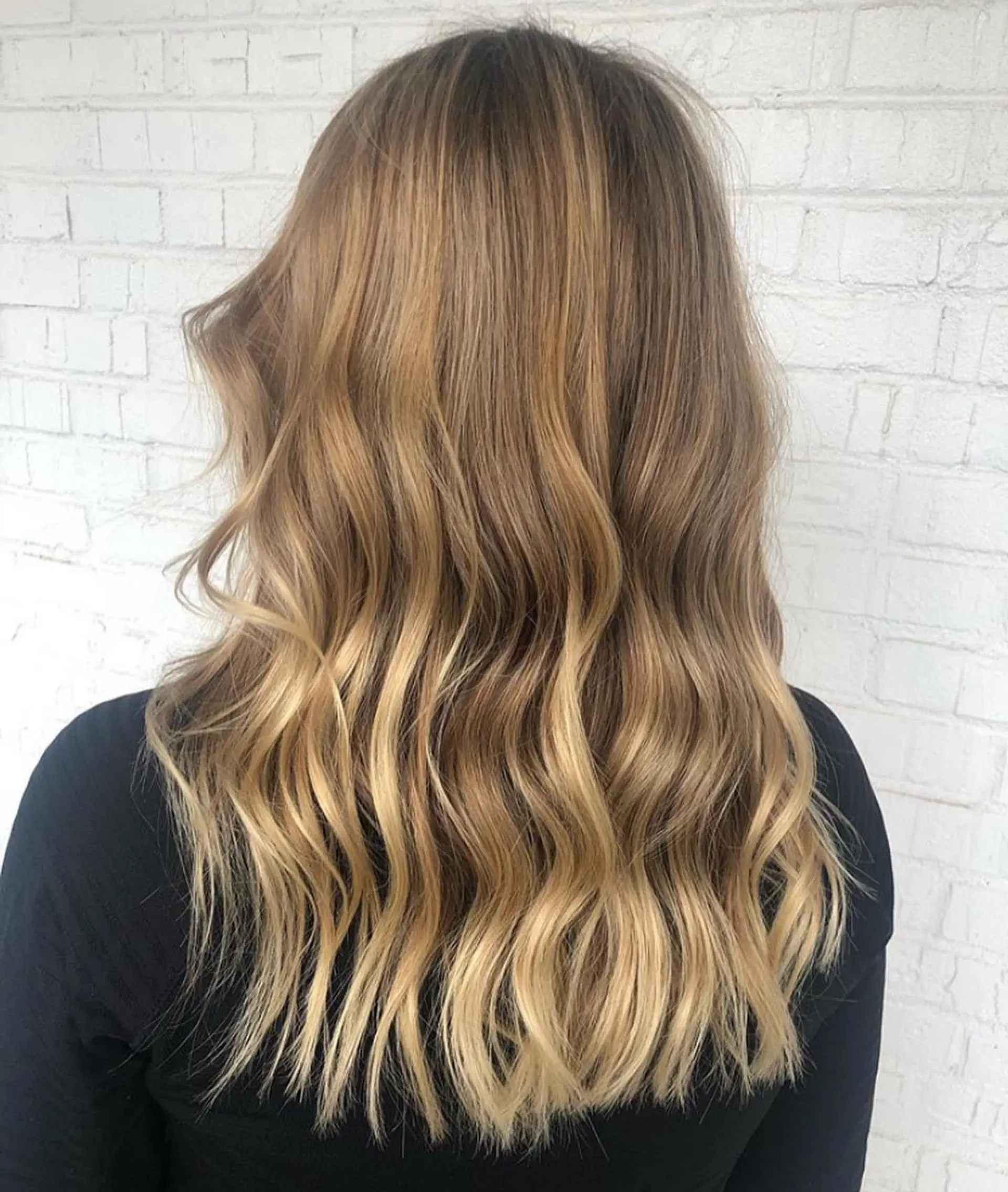 Long hair styled in soft, undone waves with glowing golden and honey blonde partial highlights. 1