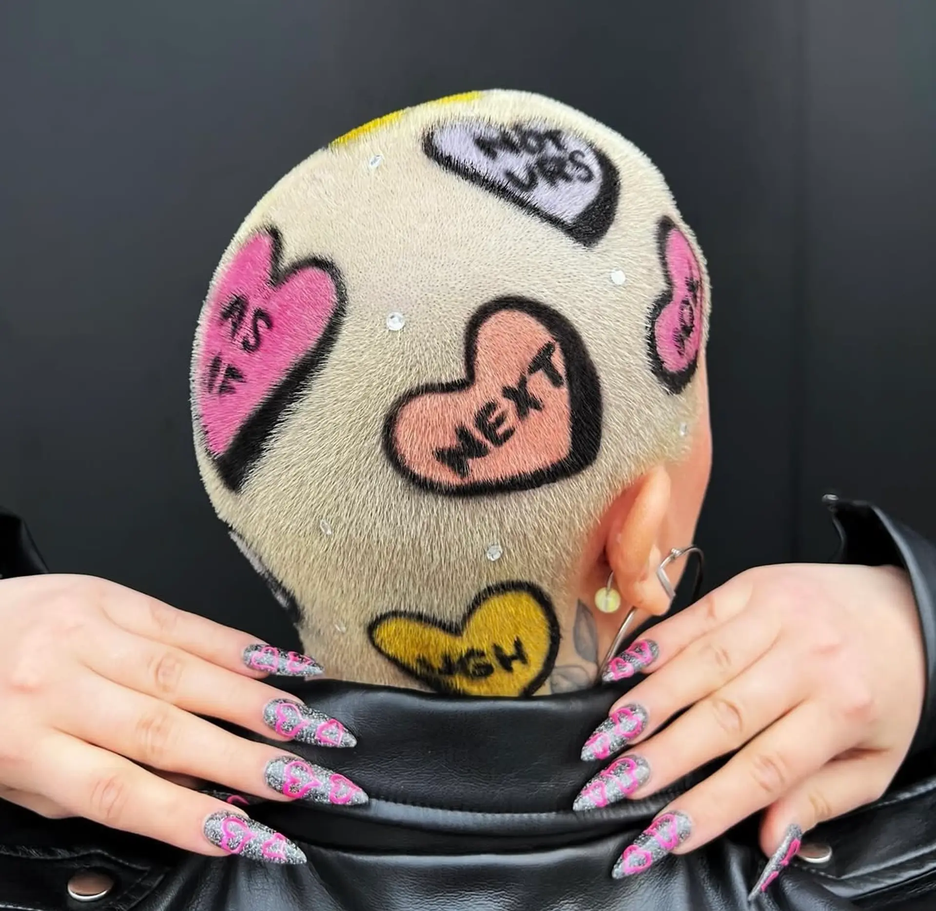 Very short buzzcut with a colorful heart hair tattoo design and rhinestone accents. 1