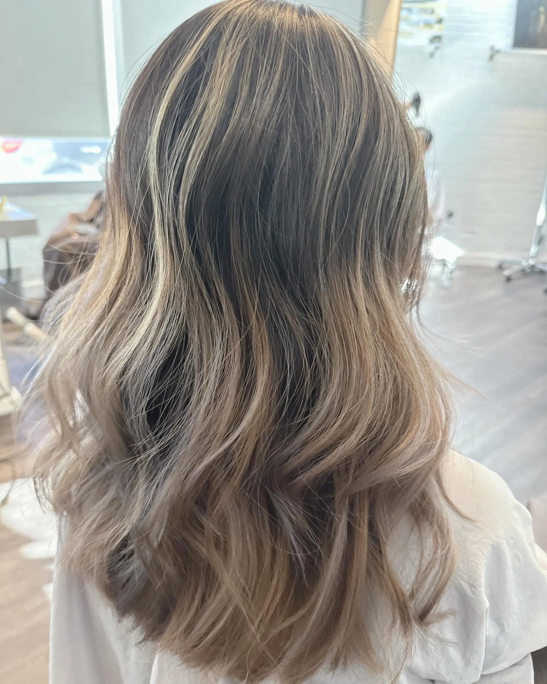 Long ash blonde and brown dimensional highlights styled in loose, soft waves. 1