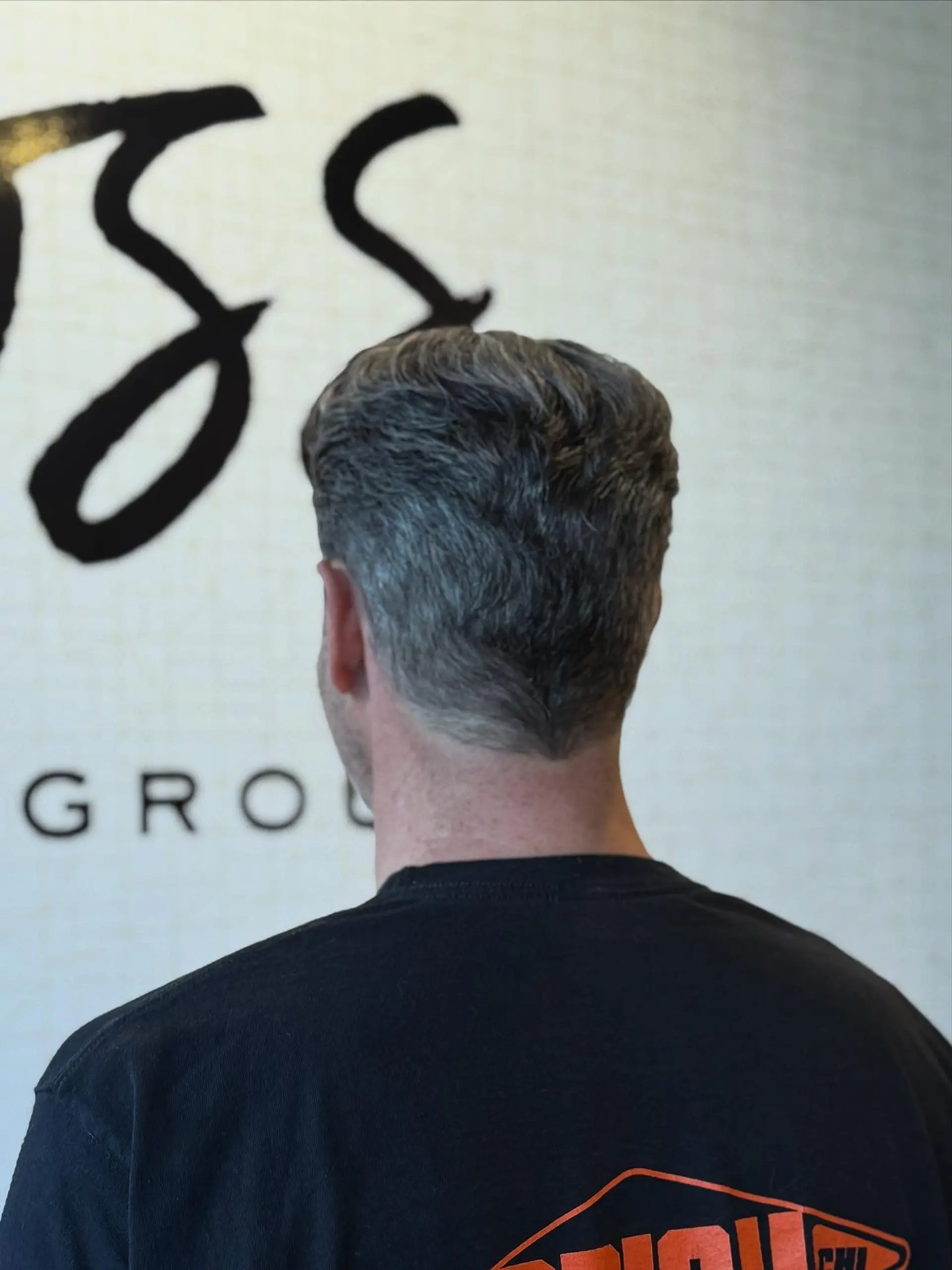 A clean, textured short haircut featuring subtle natural waves and a neatly tapered neckline. 1