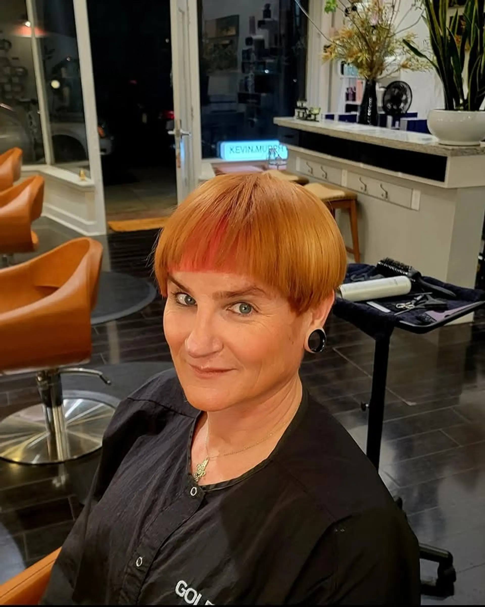 A sleek, very short bowl cut characterized by its perfectly rounded shape and a striking micro fringe that sits high on the forehead. The cut is blunt and very precise, creating a distinct, fashion-forward silhouette. 1