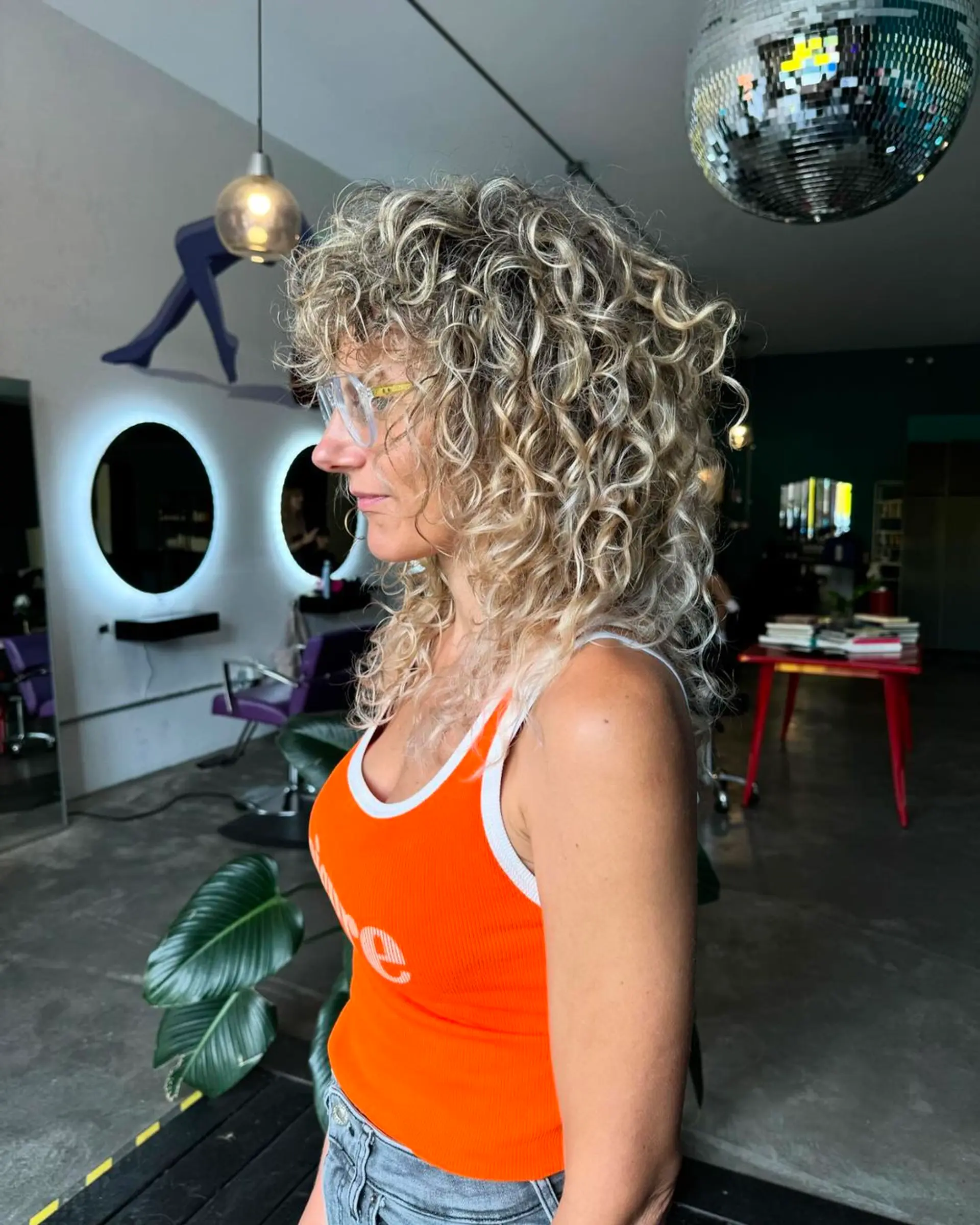 Medium-length naturally curly hairstyle in blonde and golden hues, with voluminous and bouncy spiral curls. 1