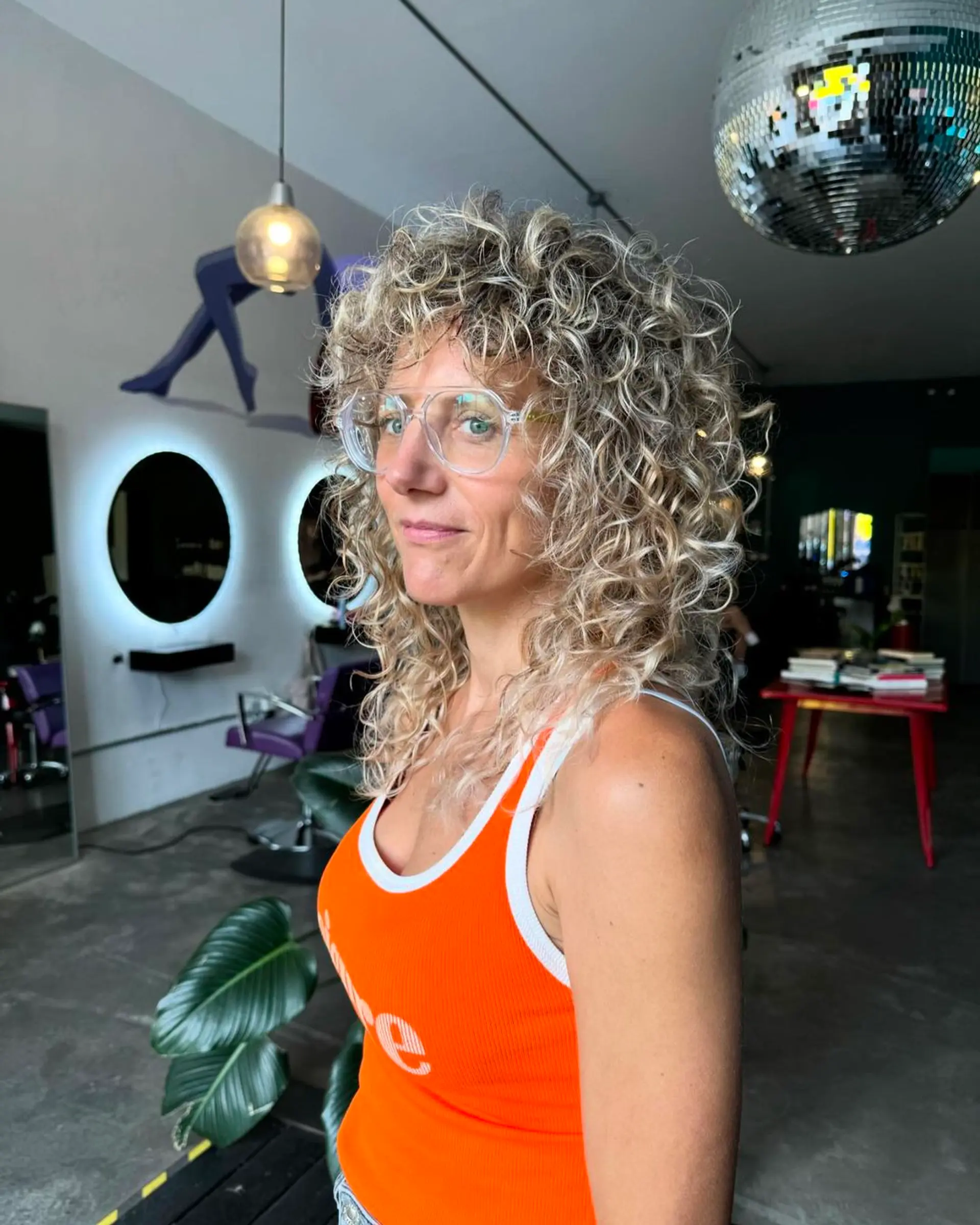 Medium-length naturally curly hairstyle in blonde and golden hues, with voluminous and bouncy spiral curls. 2