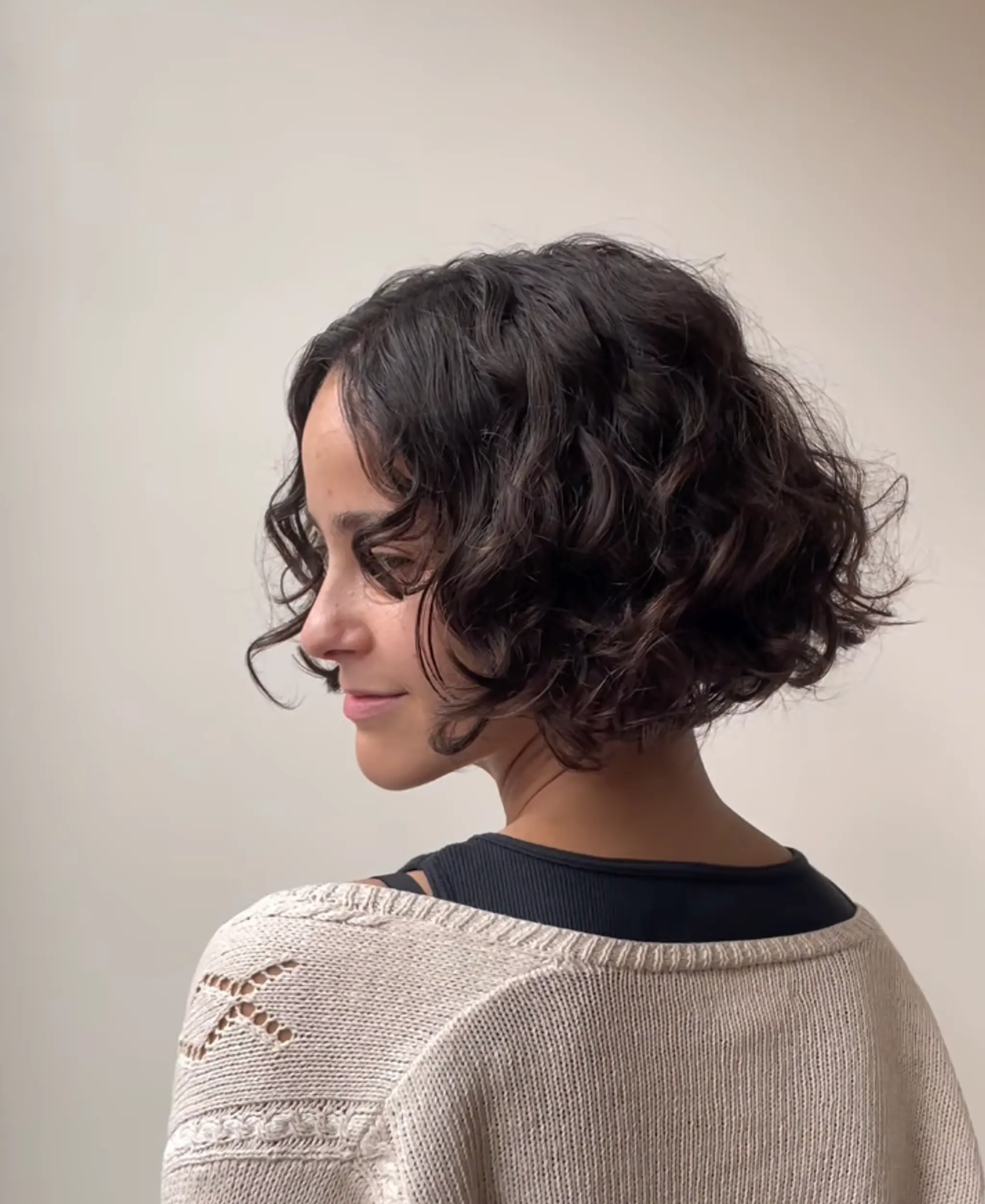 The short bob is enhanced by voluminous, defined curls. The natural dark brown tone adds depth and dimension to this playful, textured look. 1