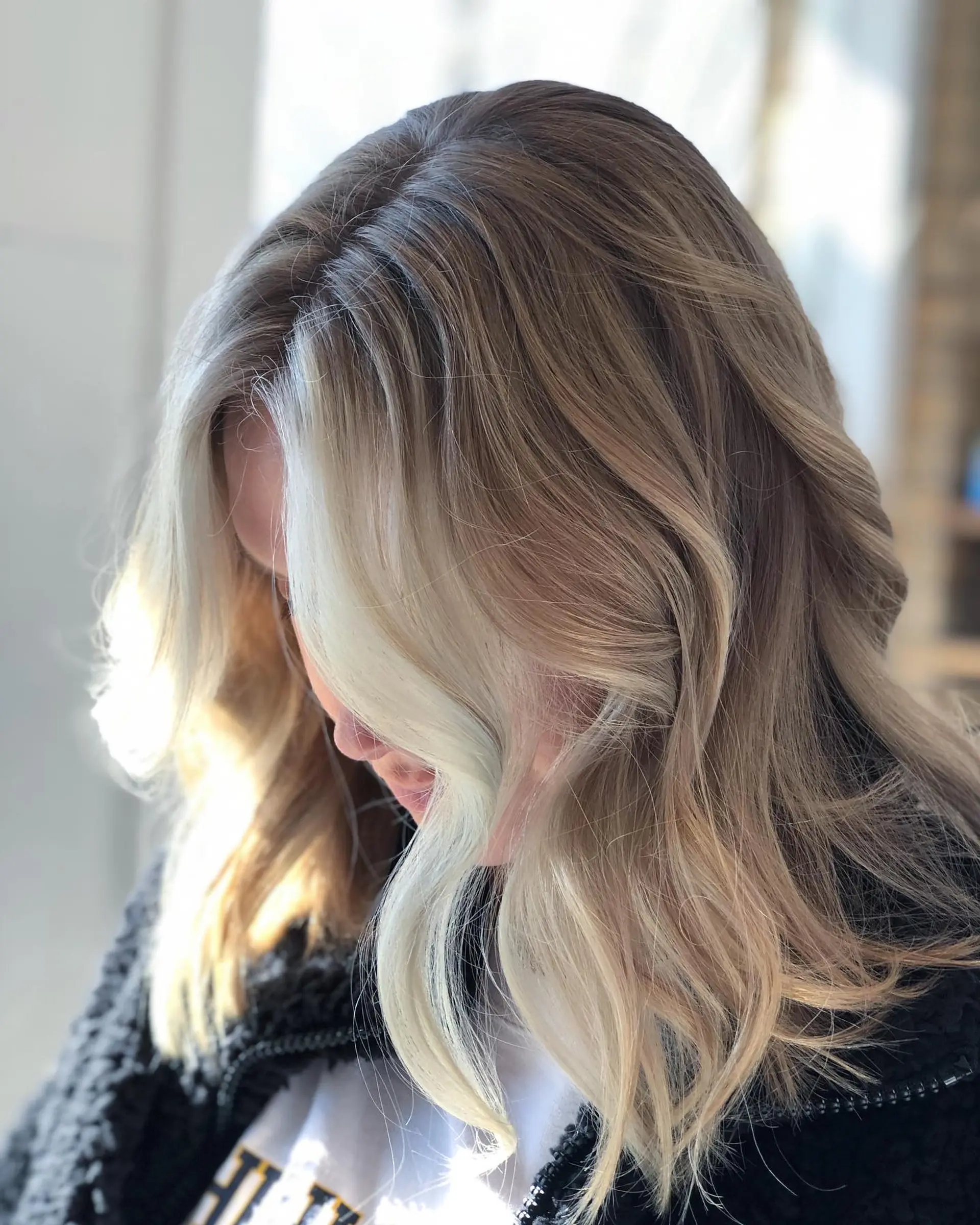Collarbone-length wavy lob featuring blended blonde balayage highlights and a prominent bright face-framing money piece. 1
