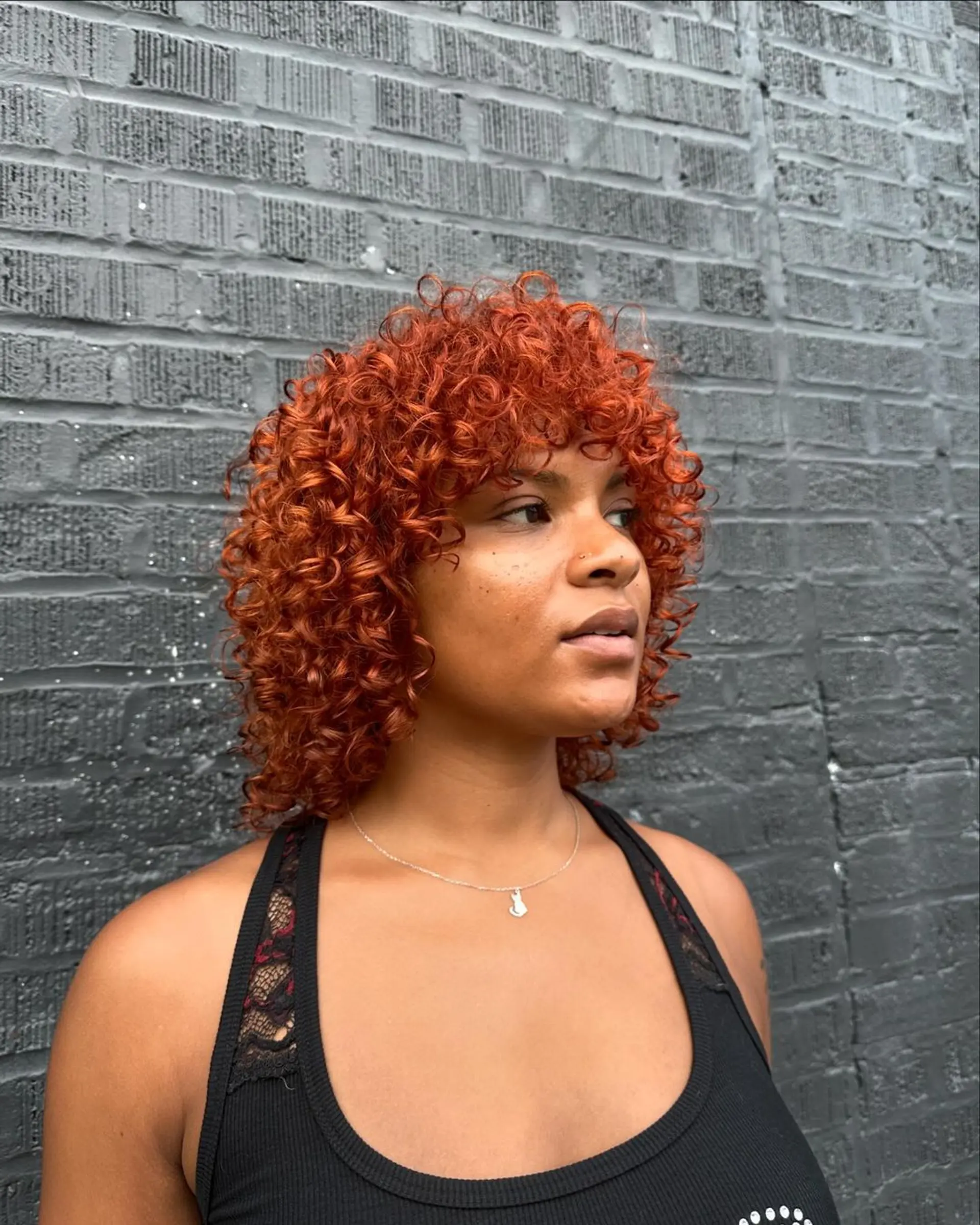 A medium-length curly bob with a vibrant copper-red color, offering voluminous and bouncy curls. 2