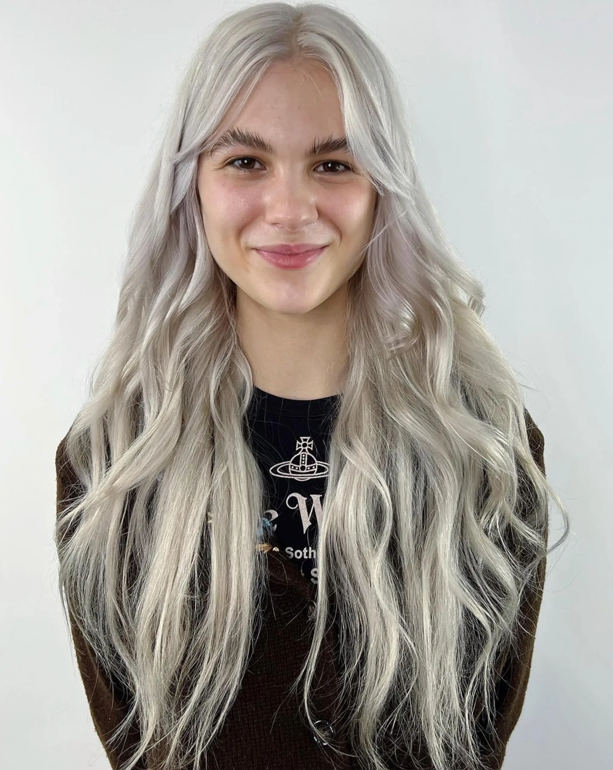 Very long, wavy platinum blonde hair parted in the center, with soft waves and cool tones.
