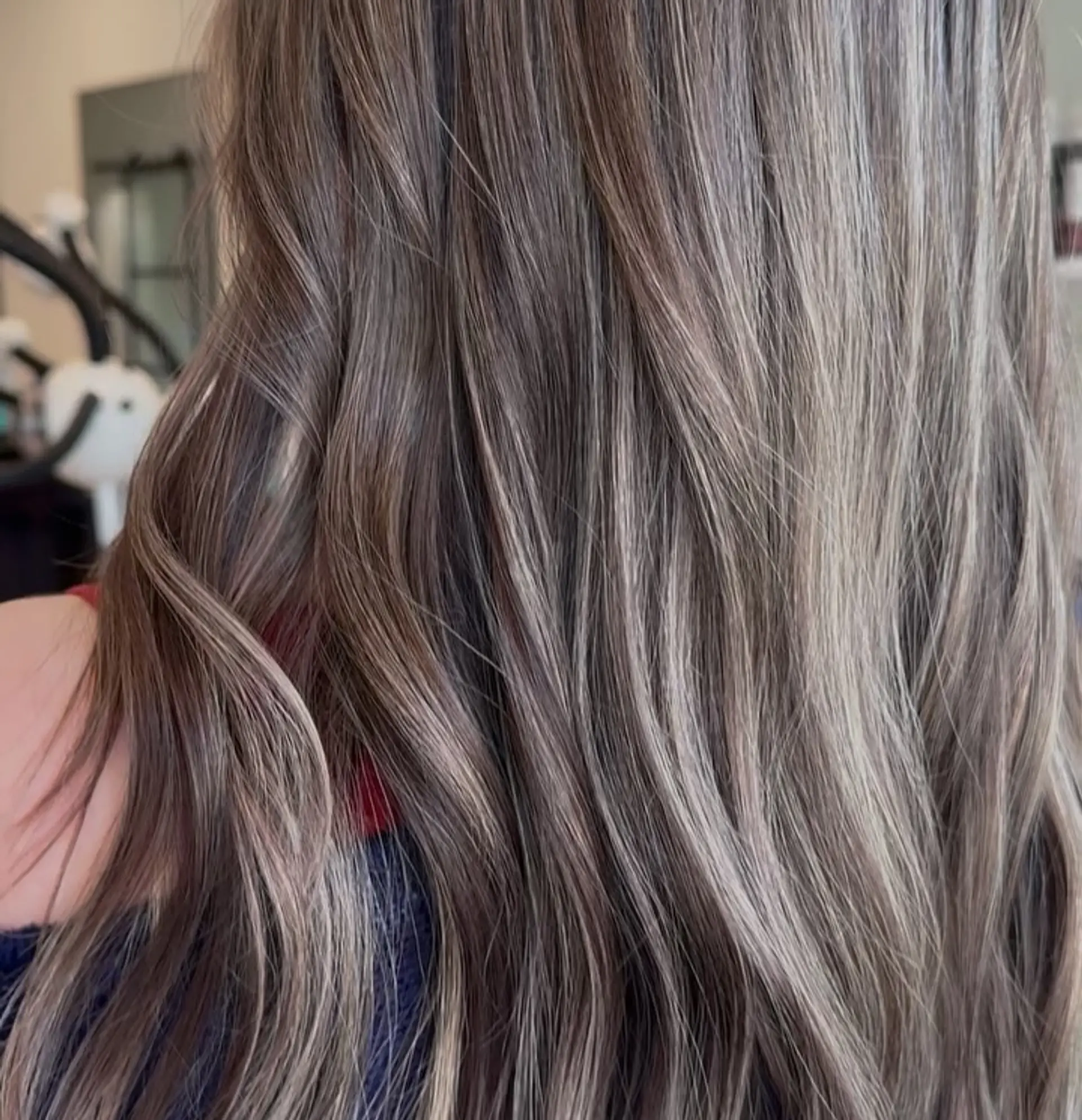 Long cool-toned dimensional hair featuring fine ash blonde highlights blended seamlessly over a mushroom brown base with subtle waves. 1