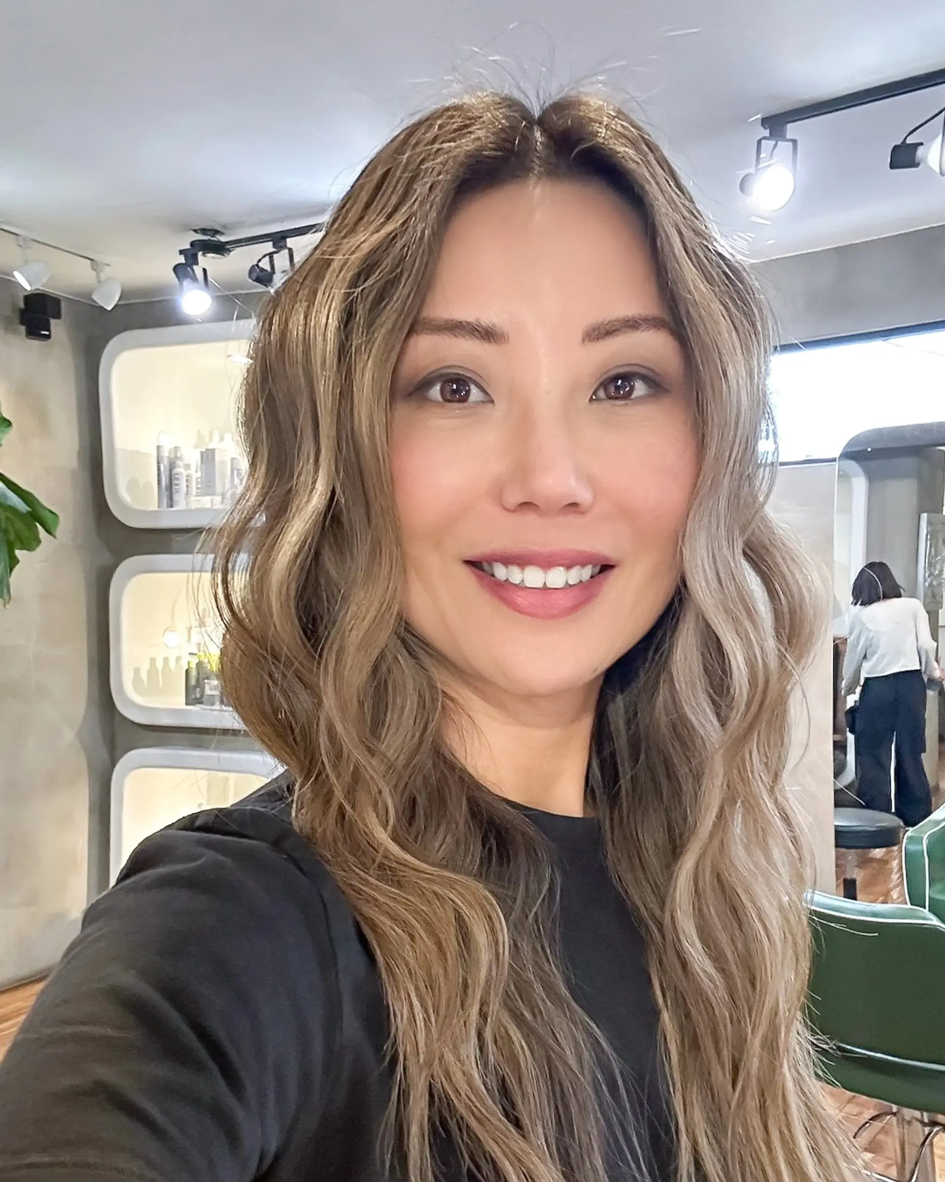 Long, flowing wavy hair styled in loose effortless waves with a dimensional bronde color blend. 1